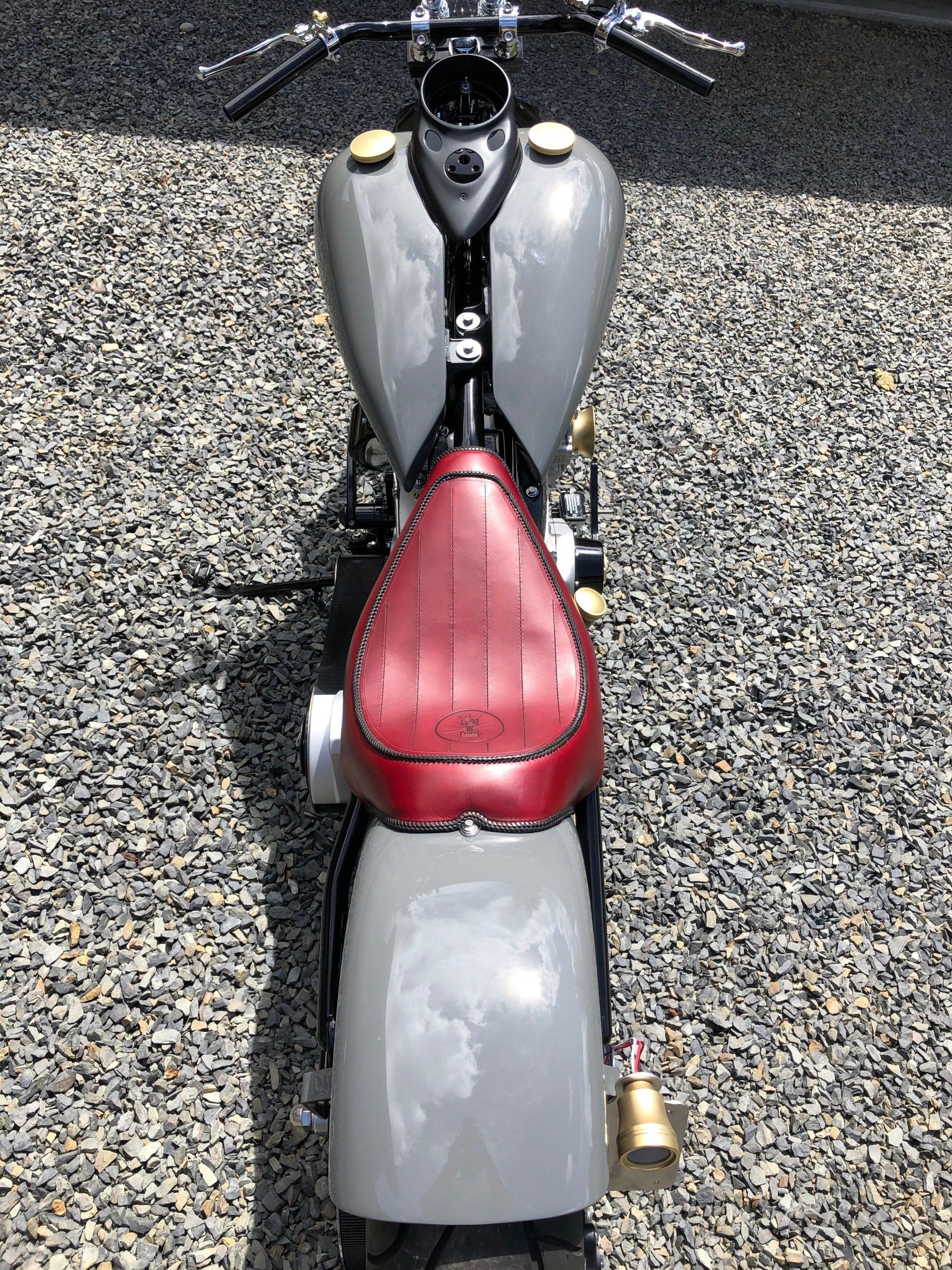 Top-down view of a gray scooter with a red seat parked on gravel