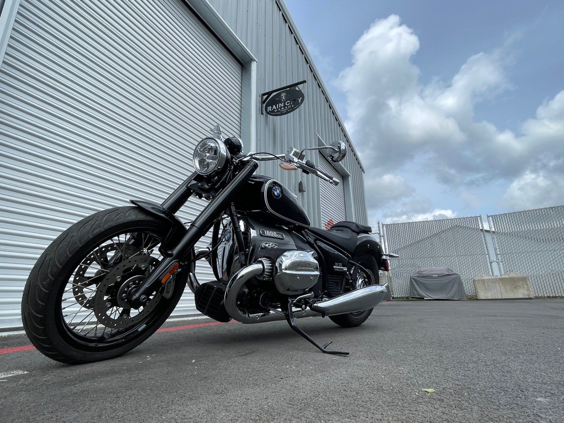 Black motorcycle parked outside a warehouse under a cloudy sky