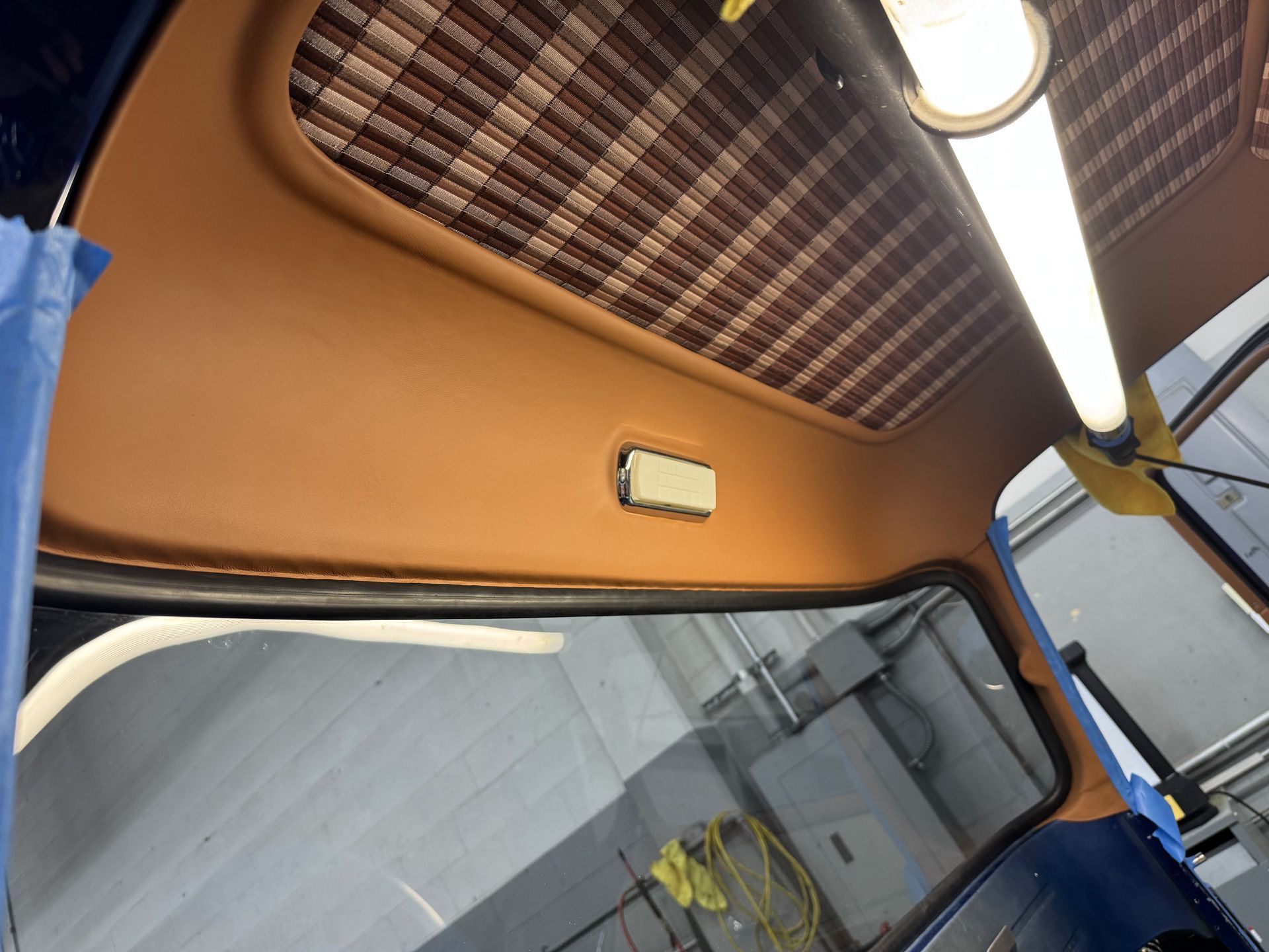 Interior of a vehicle cab with orange walls, overhead light, and a large windshield seen from below