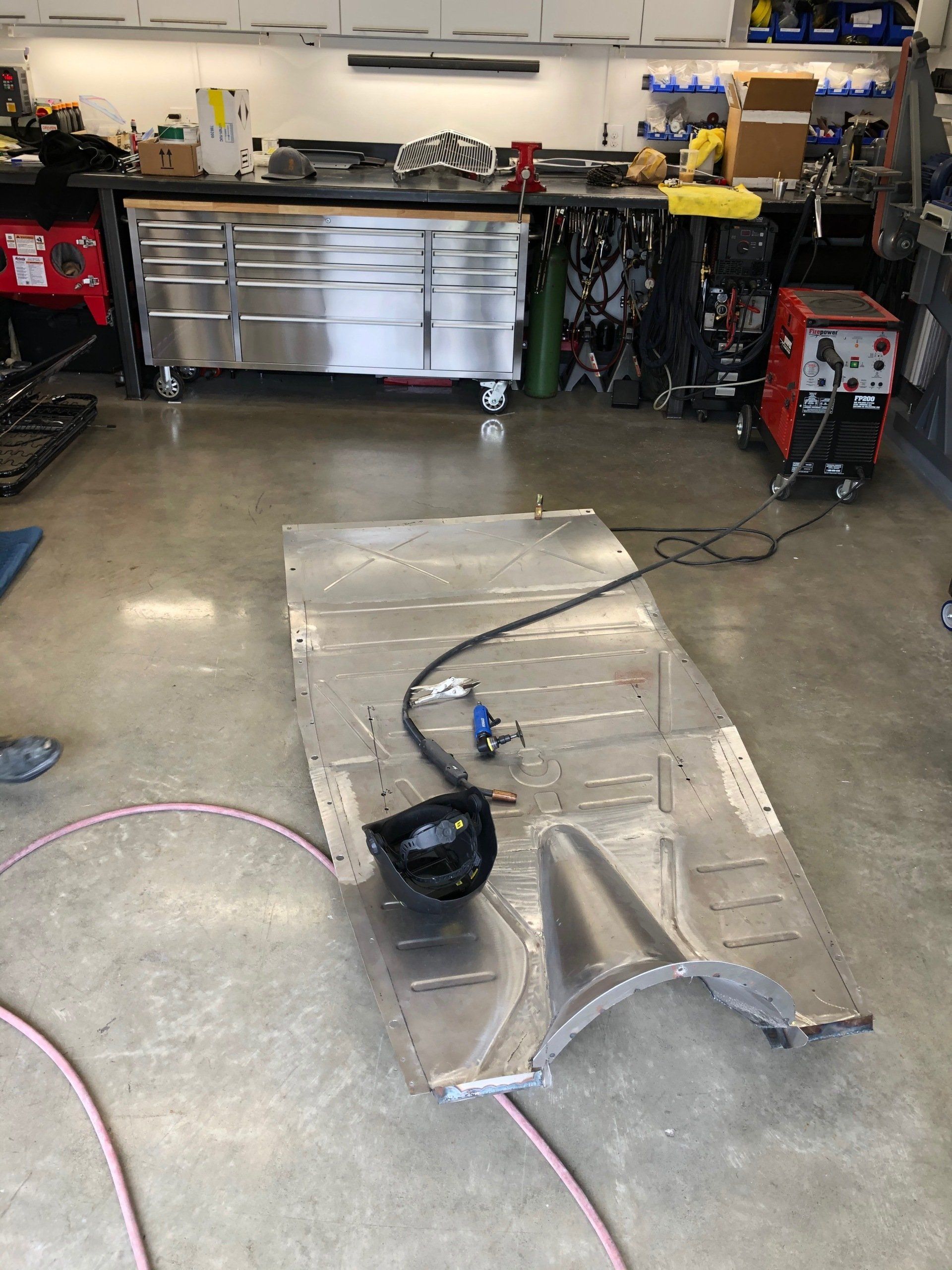 Garage floor with a clear plastic ramp, black helmet, and tools in a workshop.