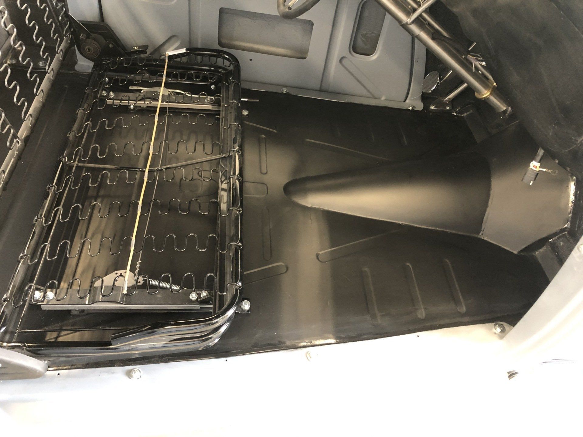 Cargo hold interior with folded metal seat frames and a large black panel on the floor