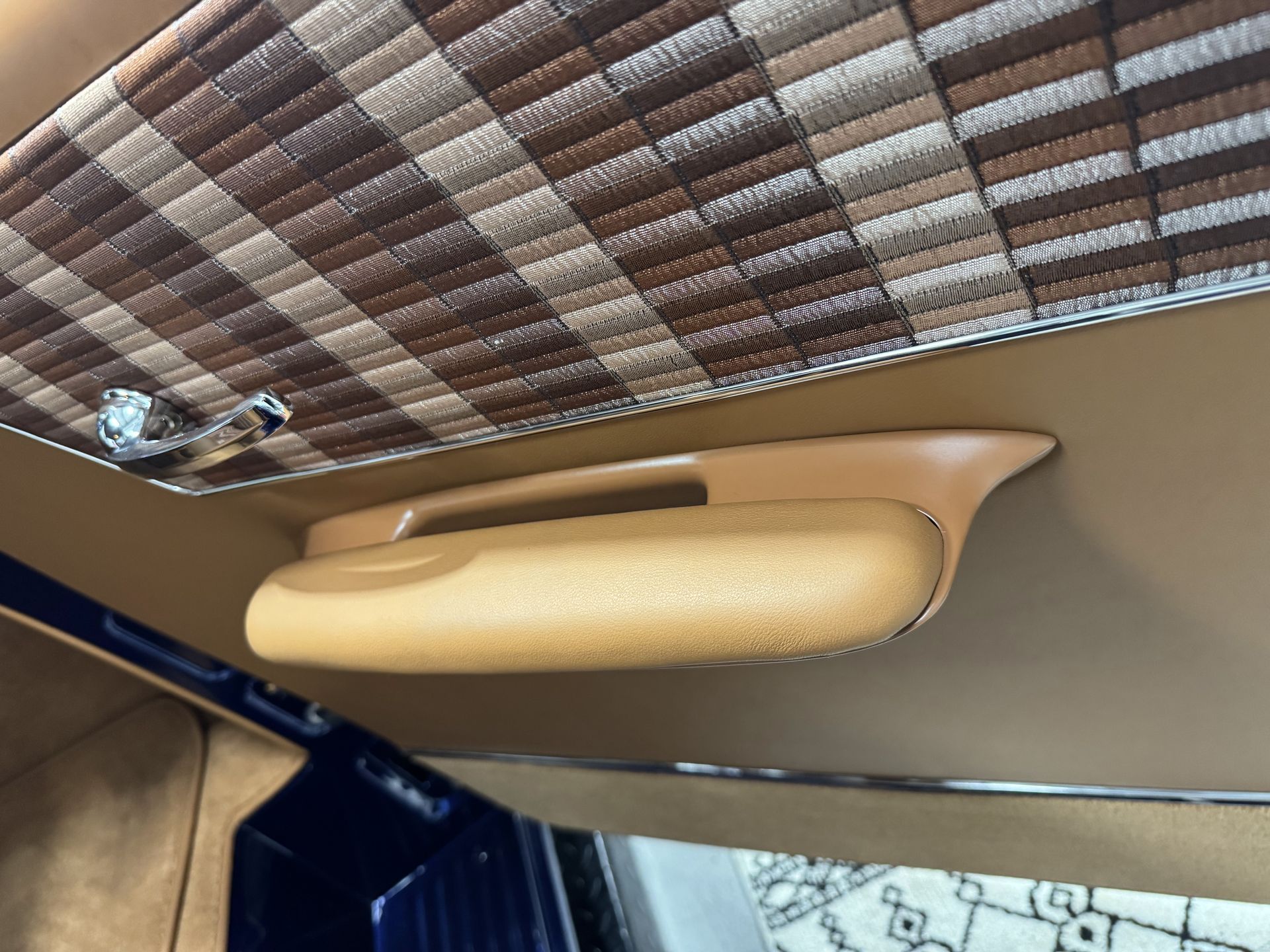 Tan upholstery door armrest beneath patterned trim inside a vehicle