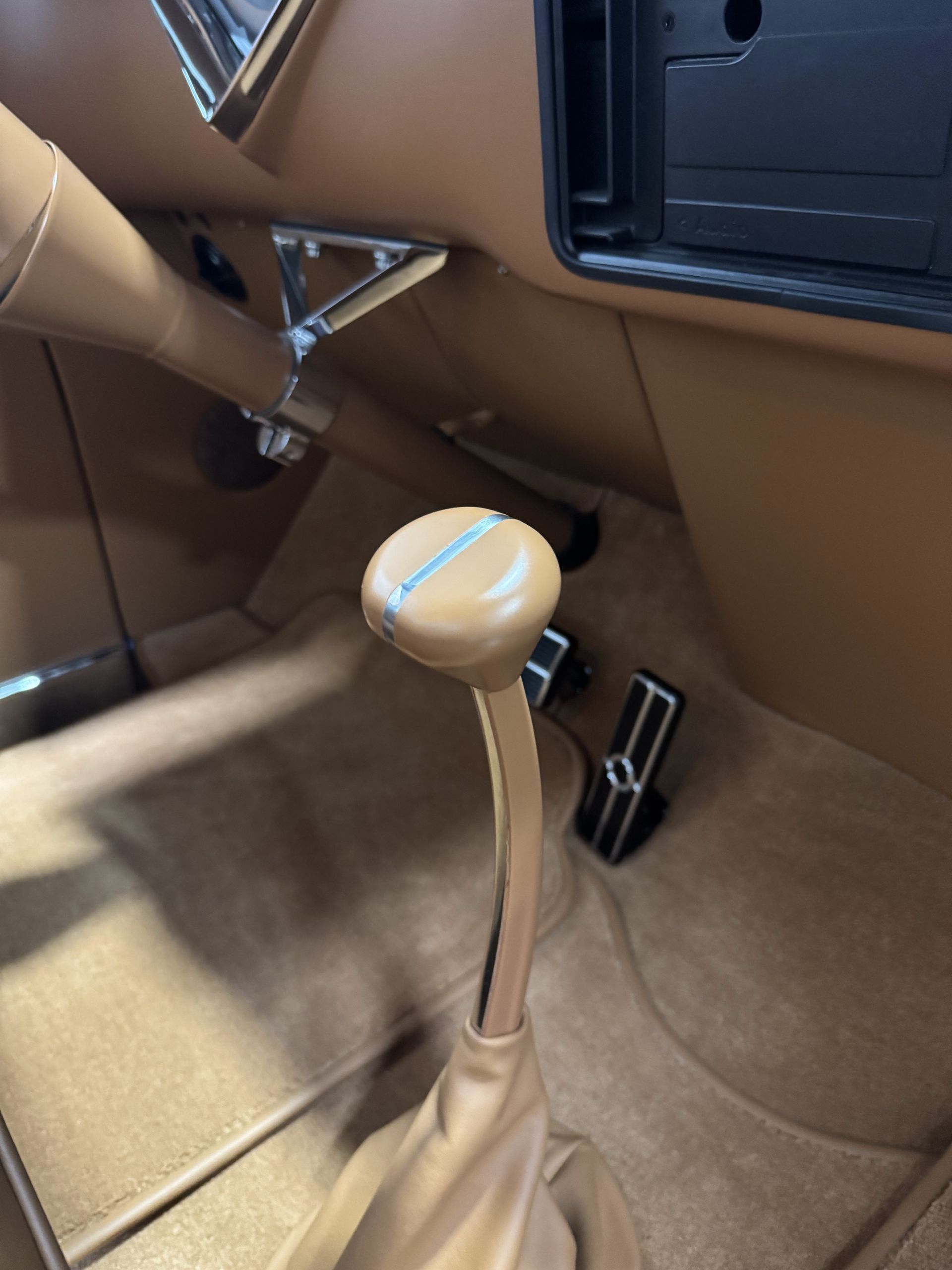 Interior of a car showing a tan manual gear shift knob and center console.