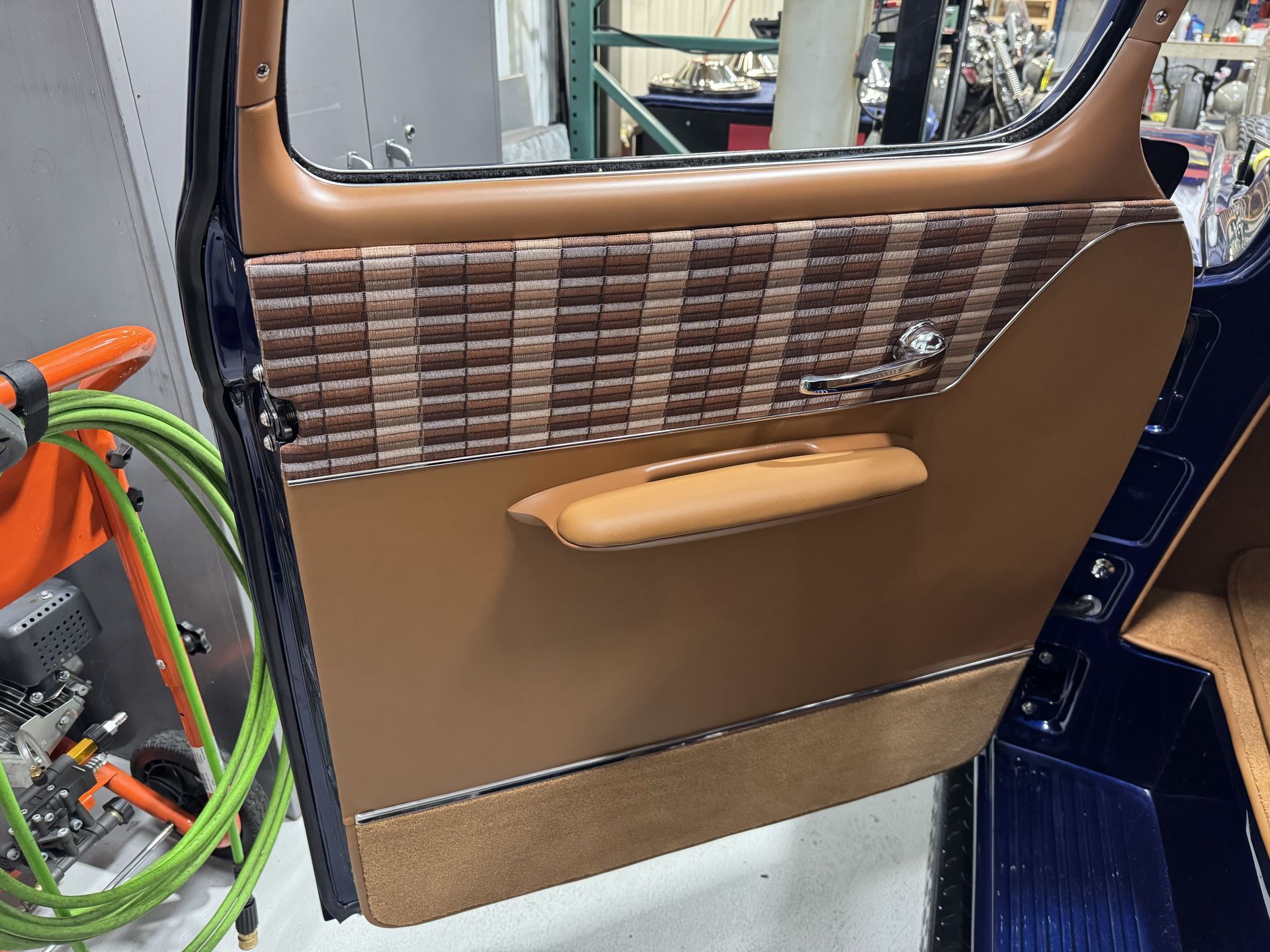 Brown car door panel with woven trim and tan handle, viewed from inside the vehicle