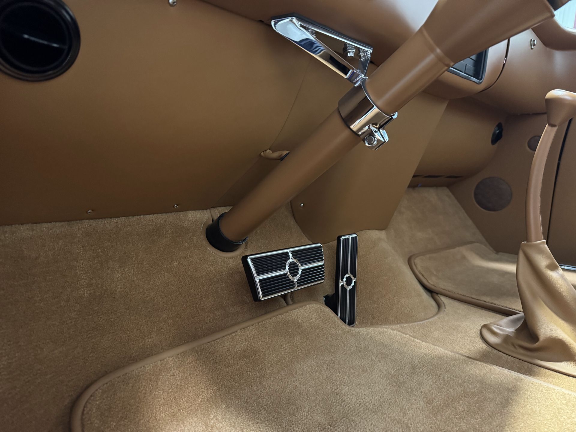 Tan leather car interior with pedals and steering column visible beneath the dashboard