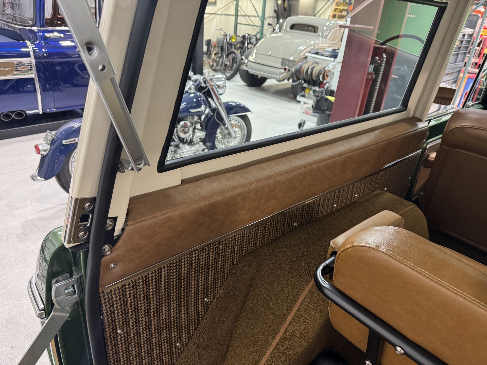 Interior of a vintage car with brown leather seats and a side window view of motorcycles in a showroom