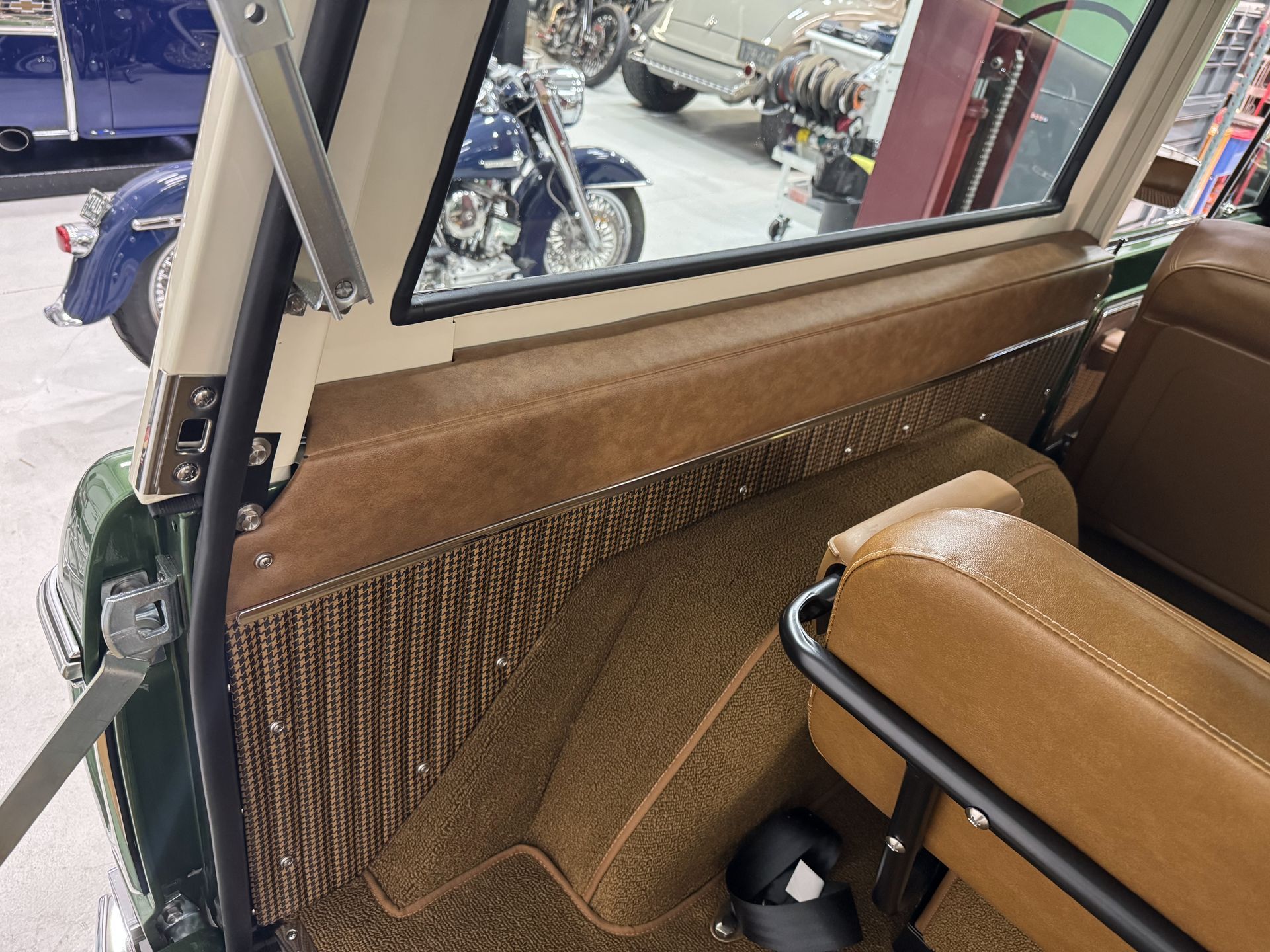 Tan interior de un coche clásico con asiento trasero, puerta abierta y vista de la calle afuera