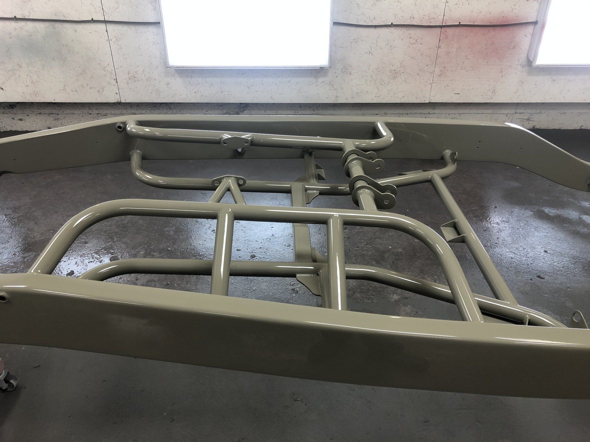 Metal pipe framework inside a room under a skylight, viewed from above.