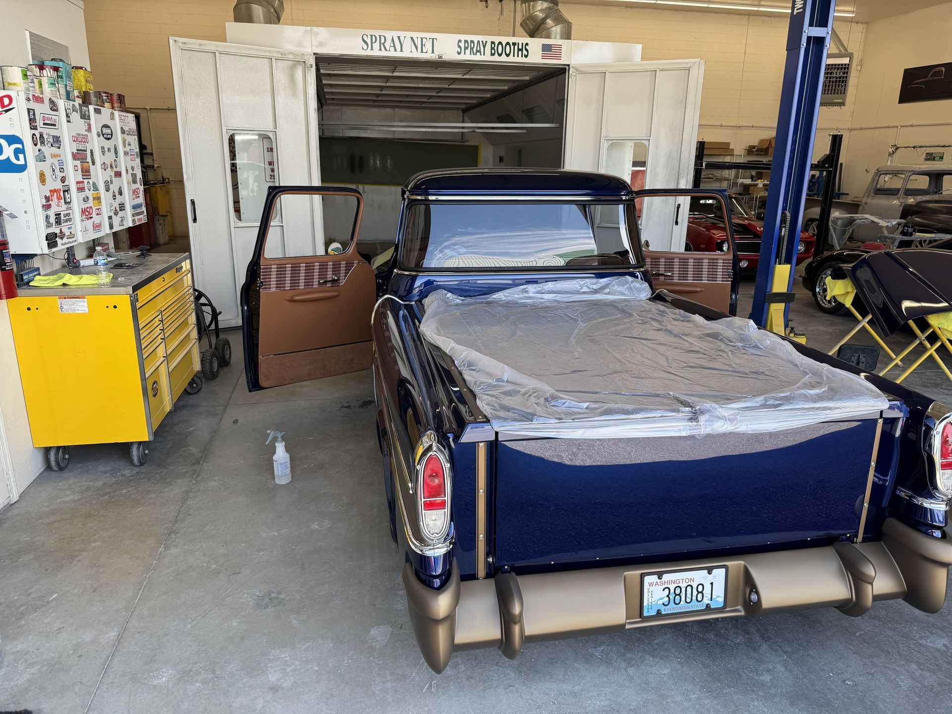 Blue vintage pickup inside a garage, with tools and boxes around it