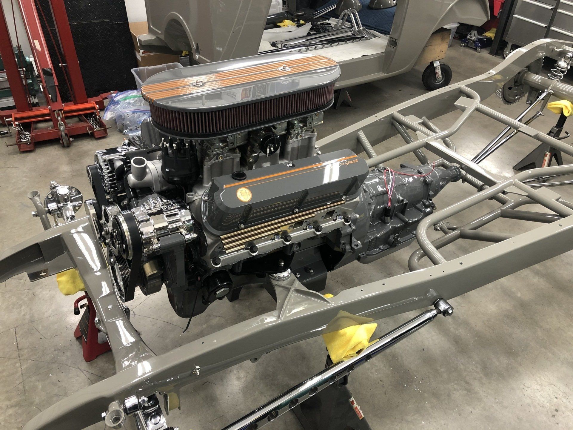 High-performance car engine mounted on a chassis frame in a garage or workshop.