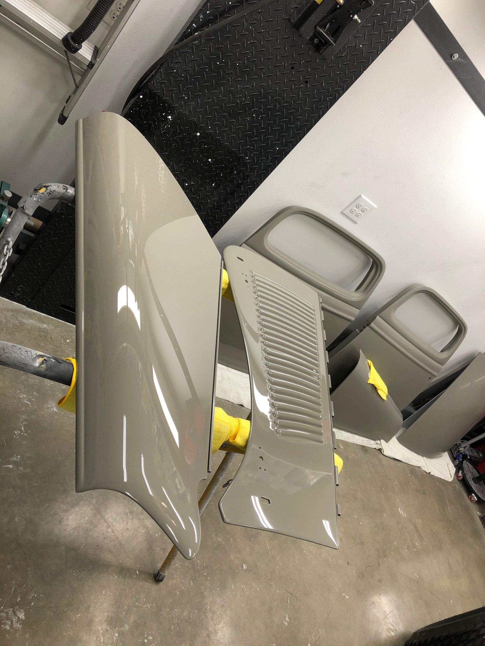 Damaged gray car parts on a concrete floor inside a garage or workshop