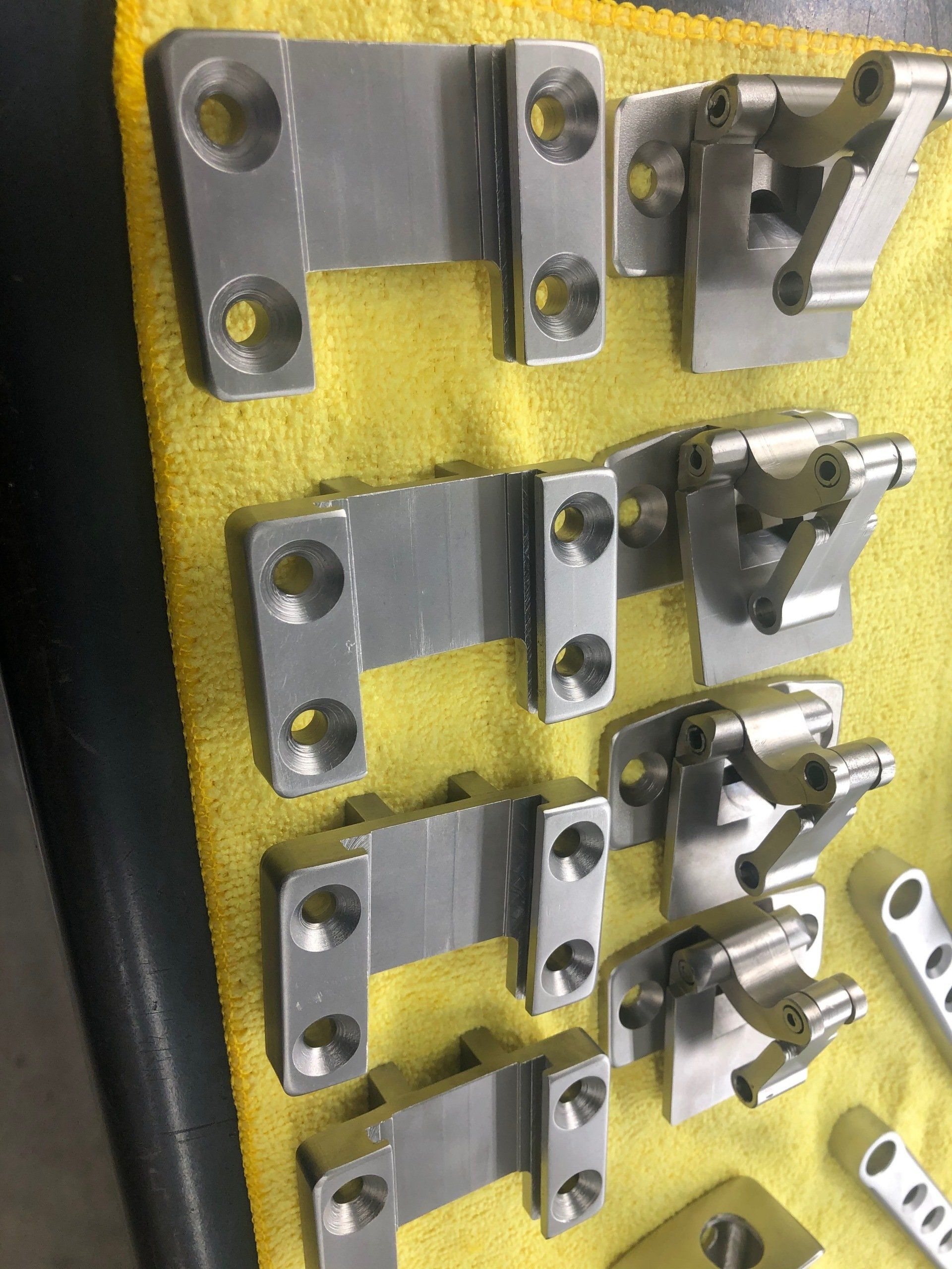 Assorted metal clamps and brackets mounted on a yellow display board for tooling or hardware inspection.