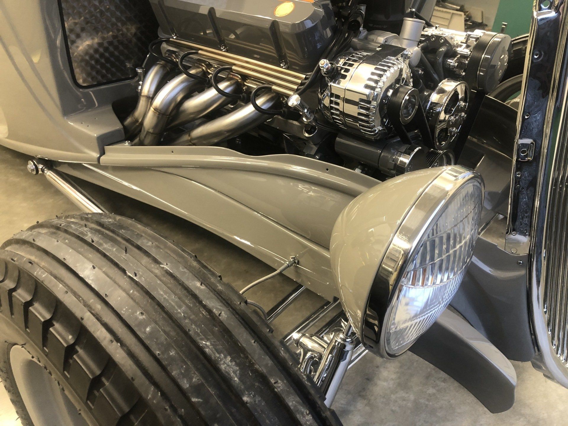 Custom hot rod front end with chrome engine, exposed exhaust headers, and wide treaded front tire