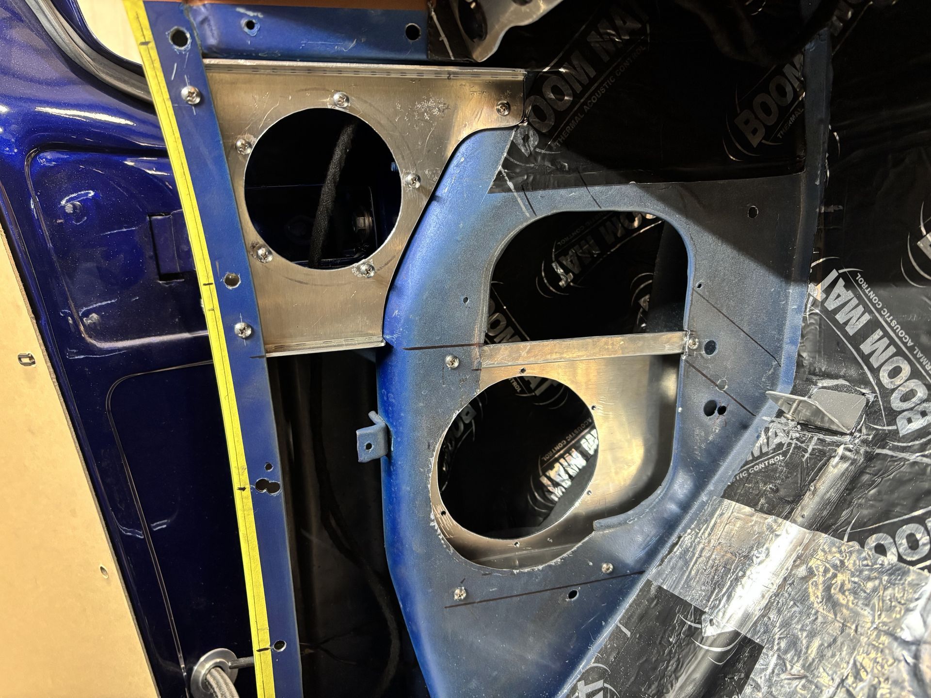 Metal car body interior with three large circular cutouts and blue painted paneling, viewed close up