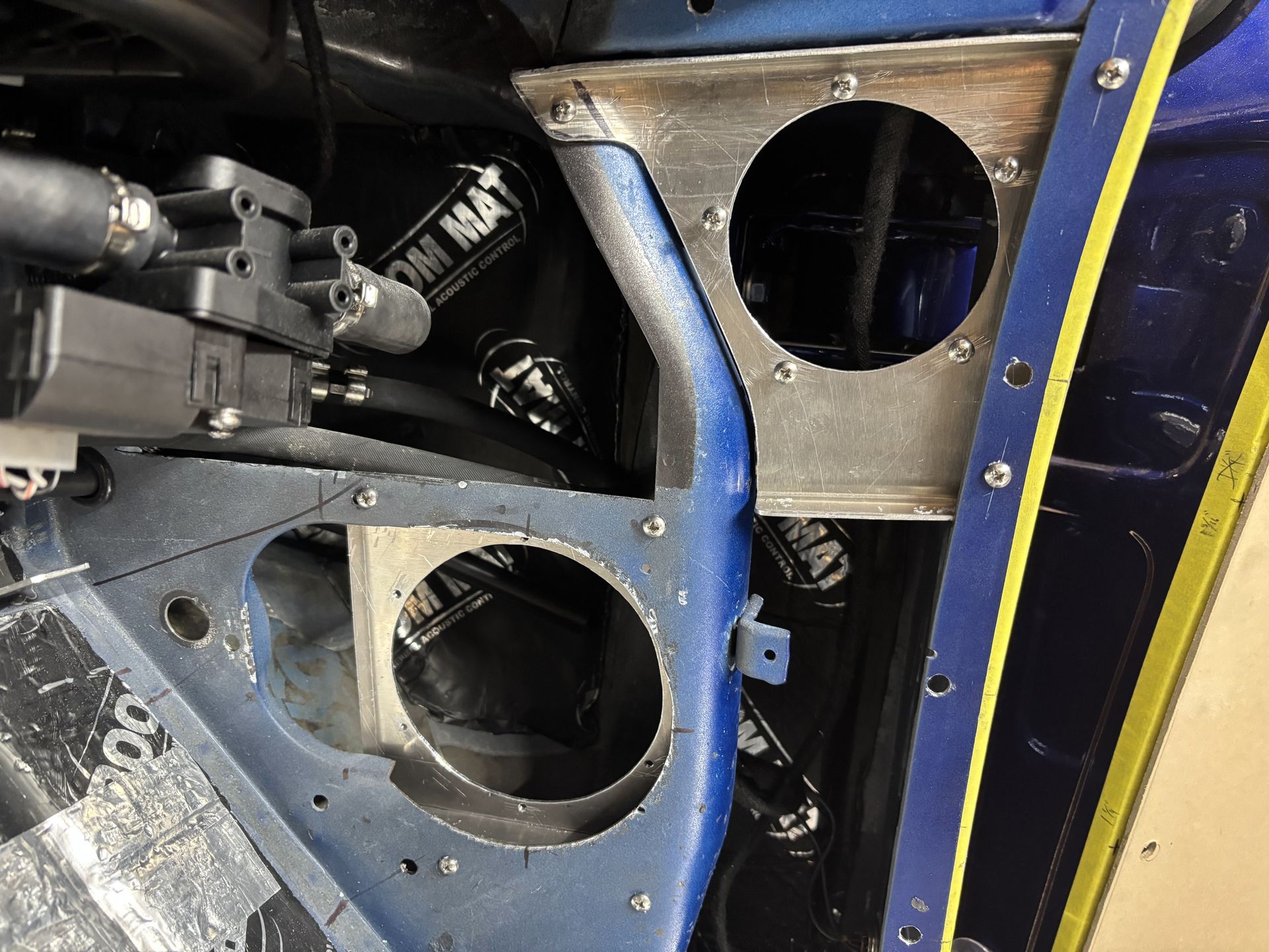 Blue metal frame with circular openings and hoses inside a vehicle or machine compartment