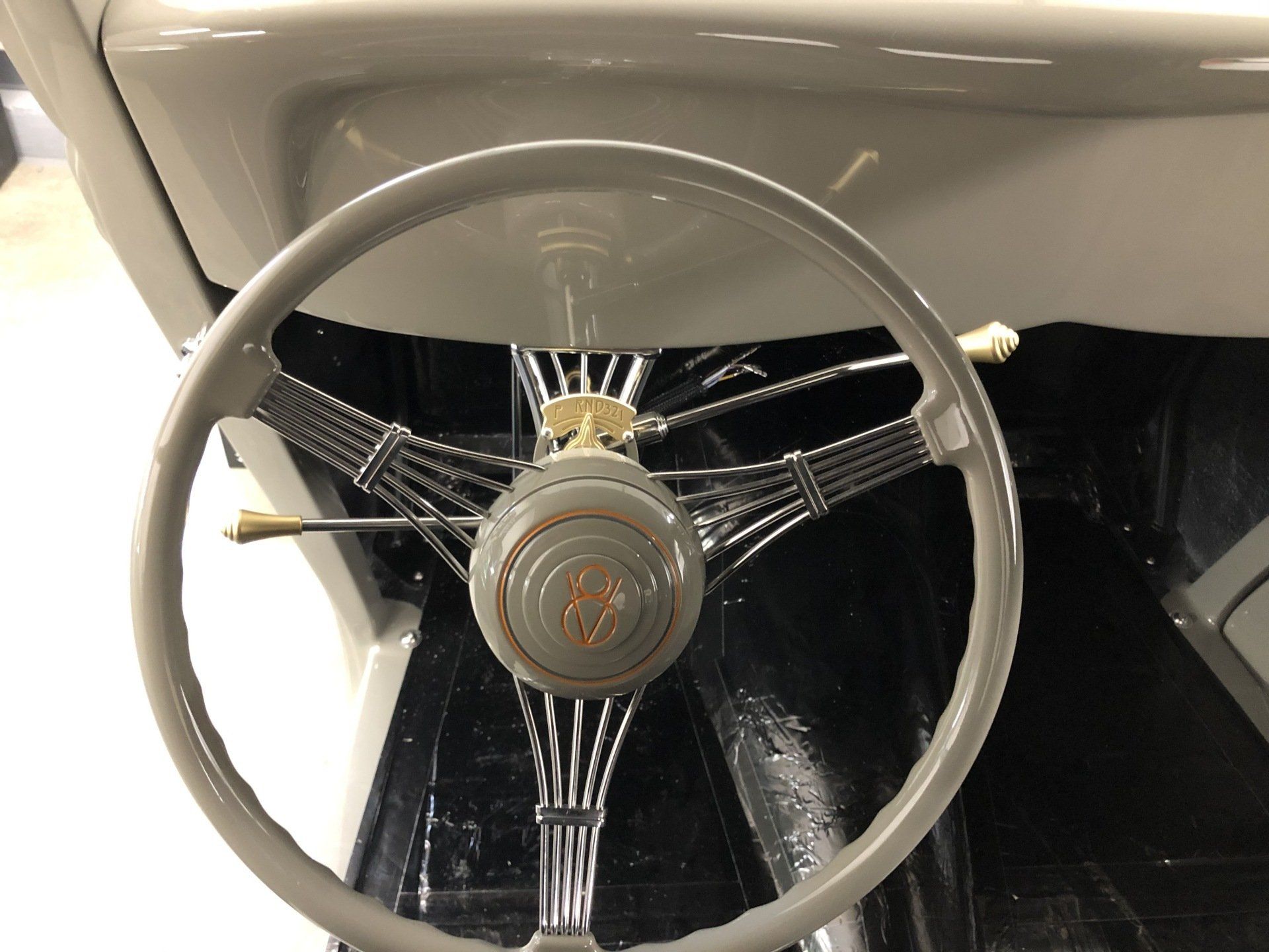 Vintage car steering wheel and dashboard interior, beige and black with chrome accents