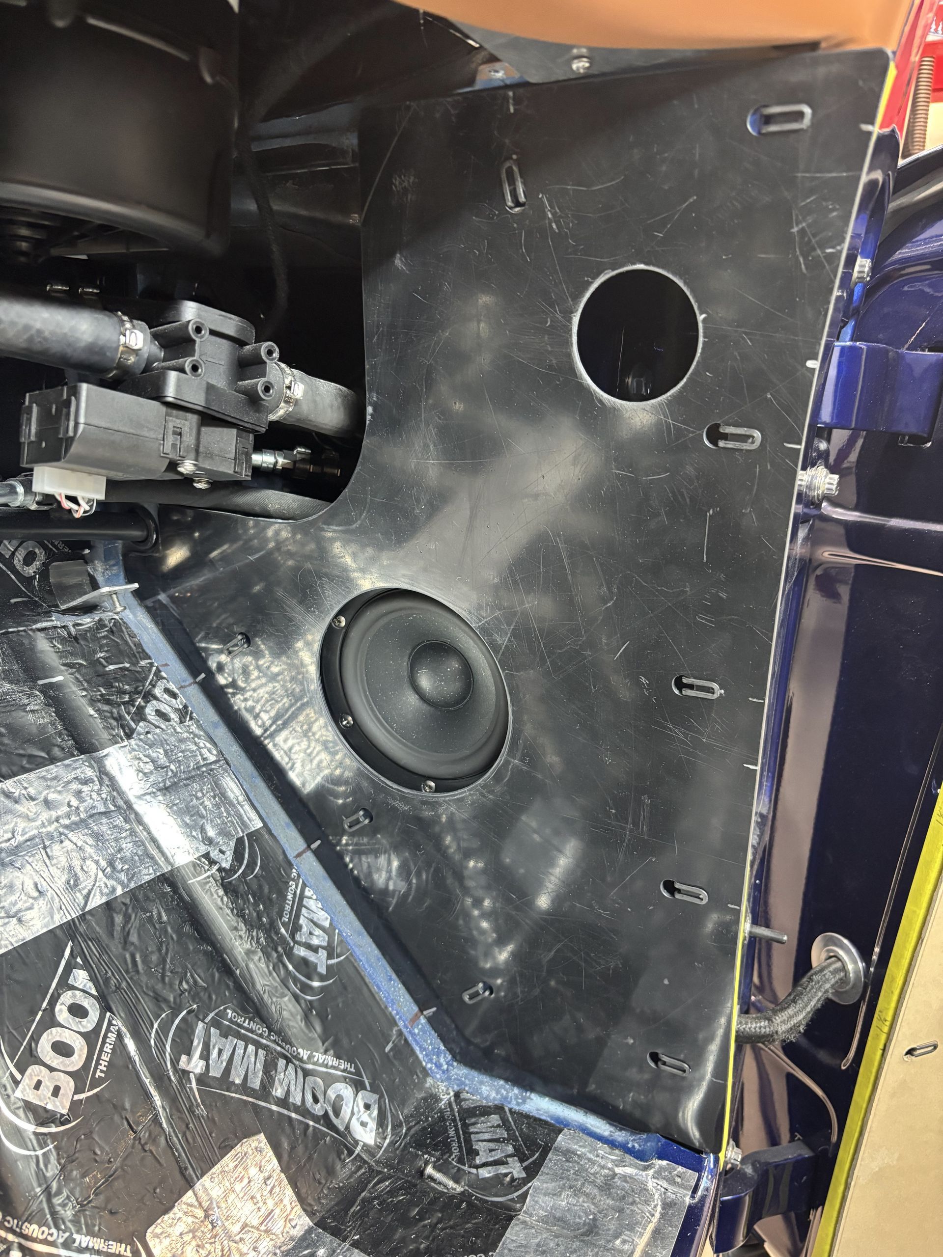 Black car trunk interior with a speaker and round cutout on a black panel