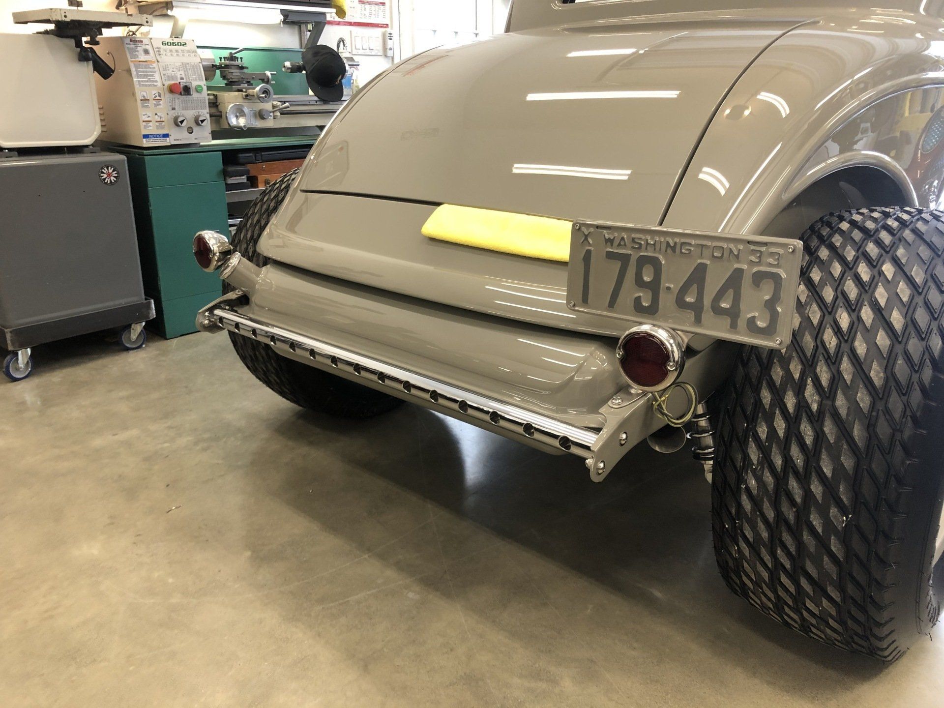 Vintage car rear in a garage, with oversized rear tires and a license plate visible.