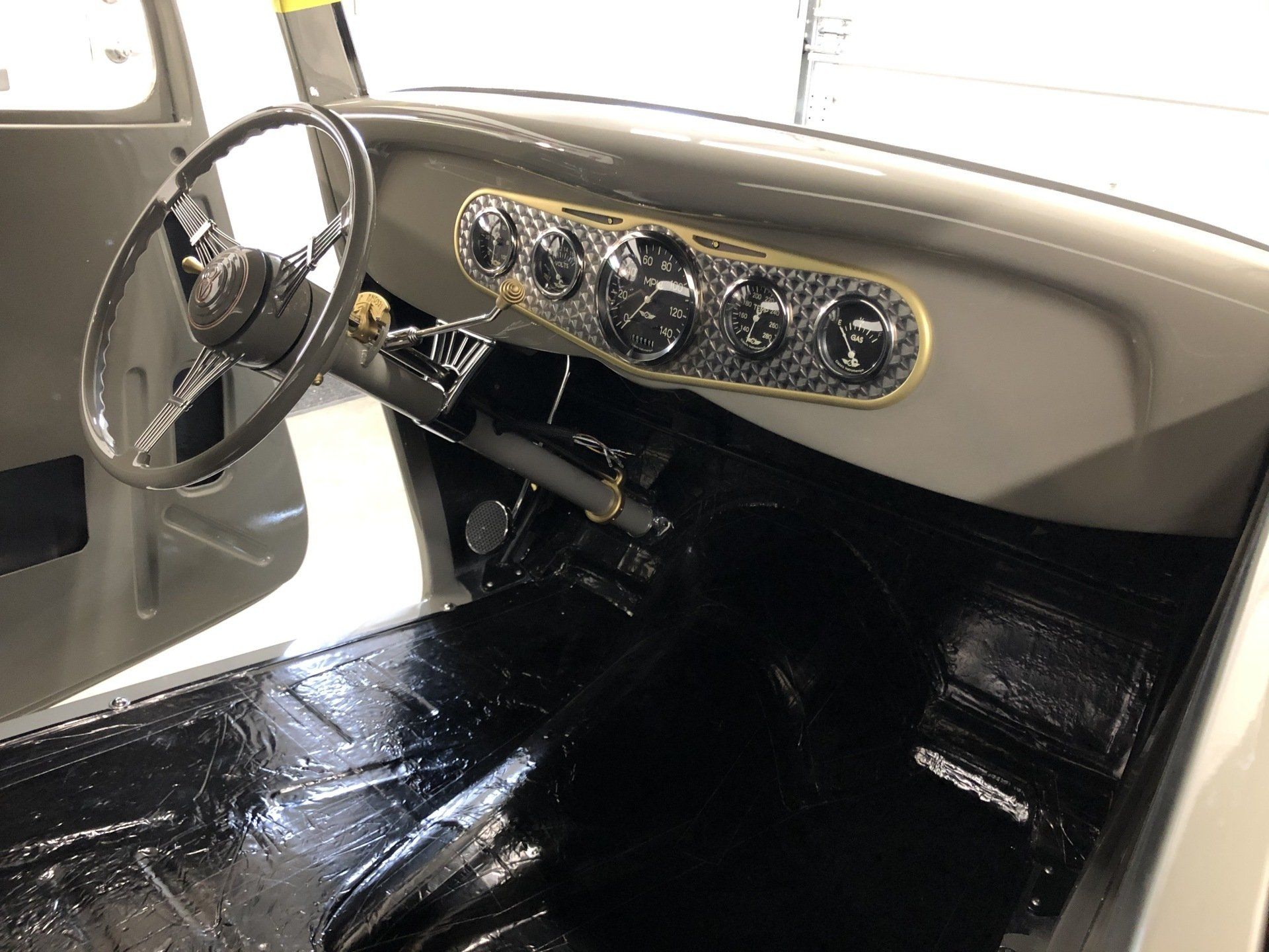 Classic car interior with white steering wheel and beige dashboard, viewed from the driver’s seat