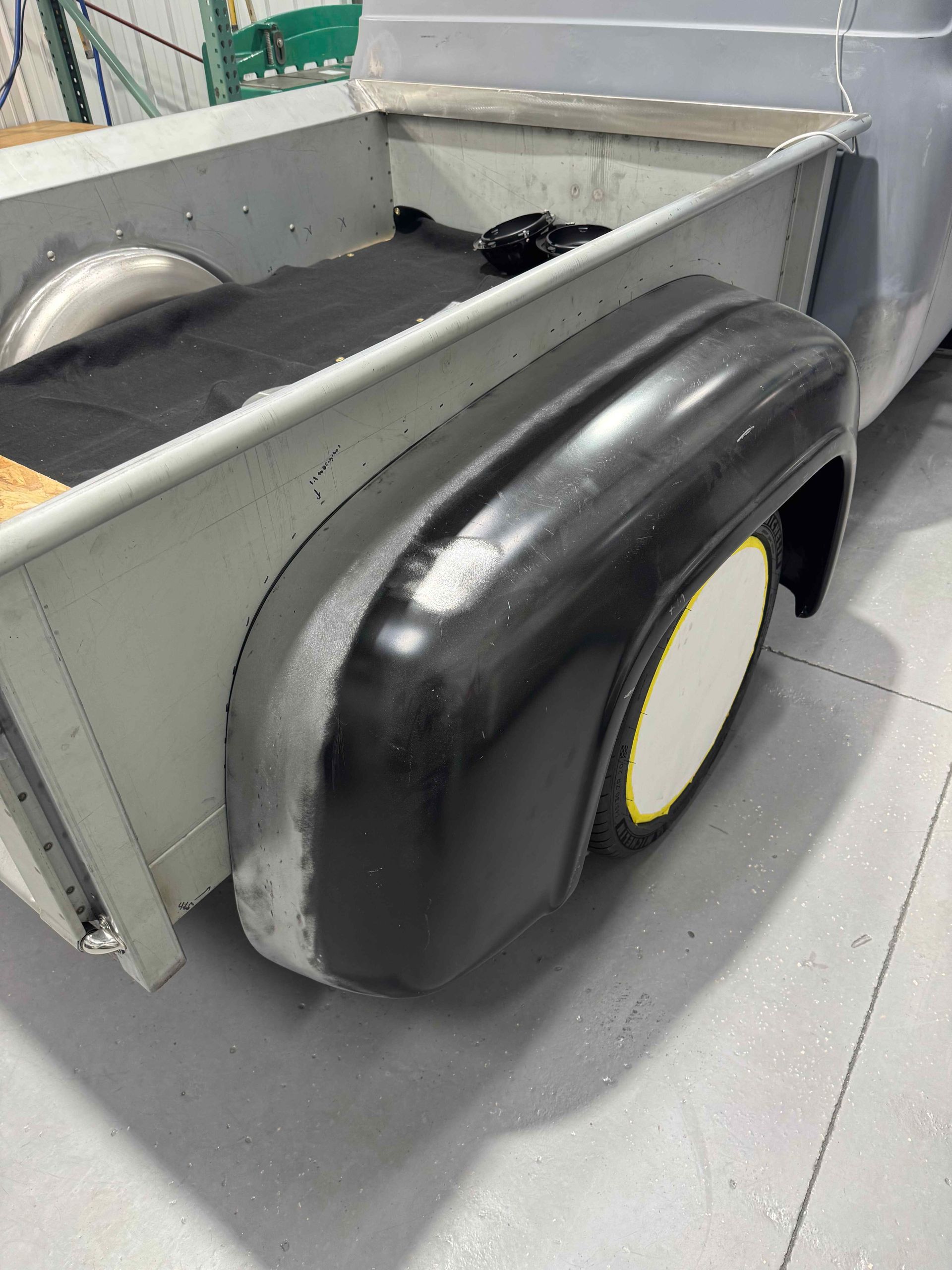 Black wheel and gray cart frame in a workshop-like setting with a tiled floor.