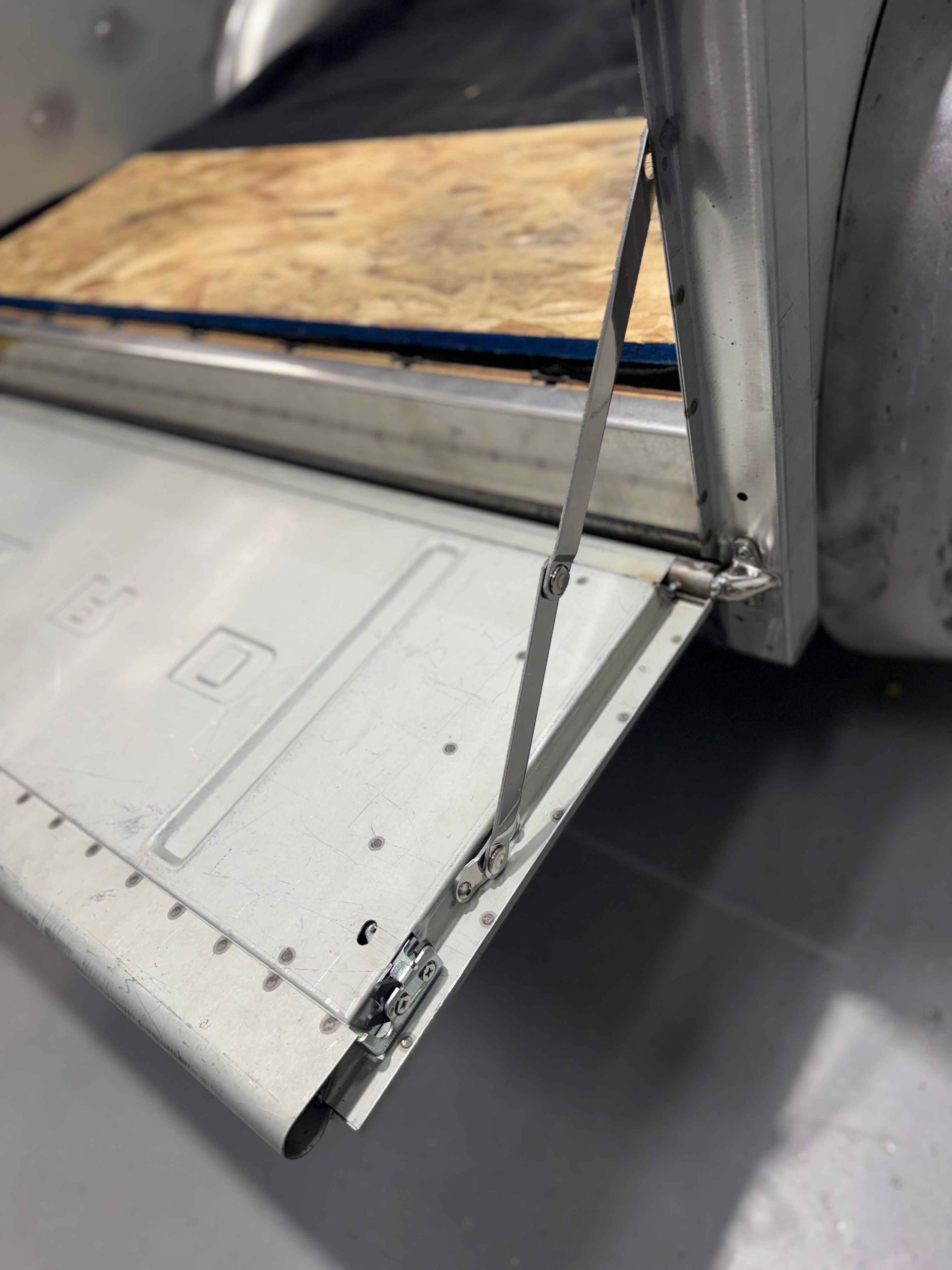 Bent metal door sill with peeling trim on a vehicle, showing damage near the wheel.