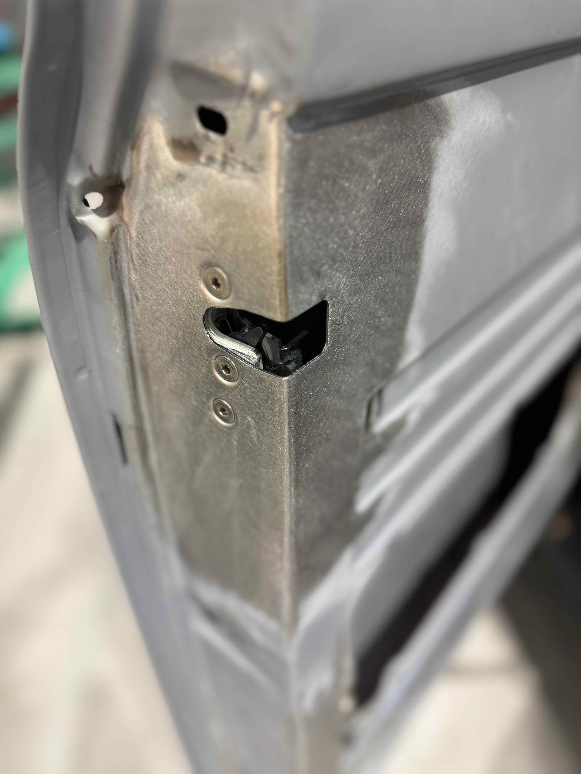 Close-up of a damaged metal corner with a torn black hole and scratches on a gray surface