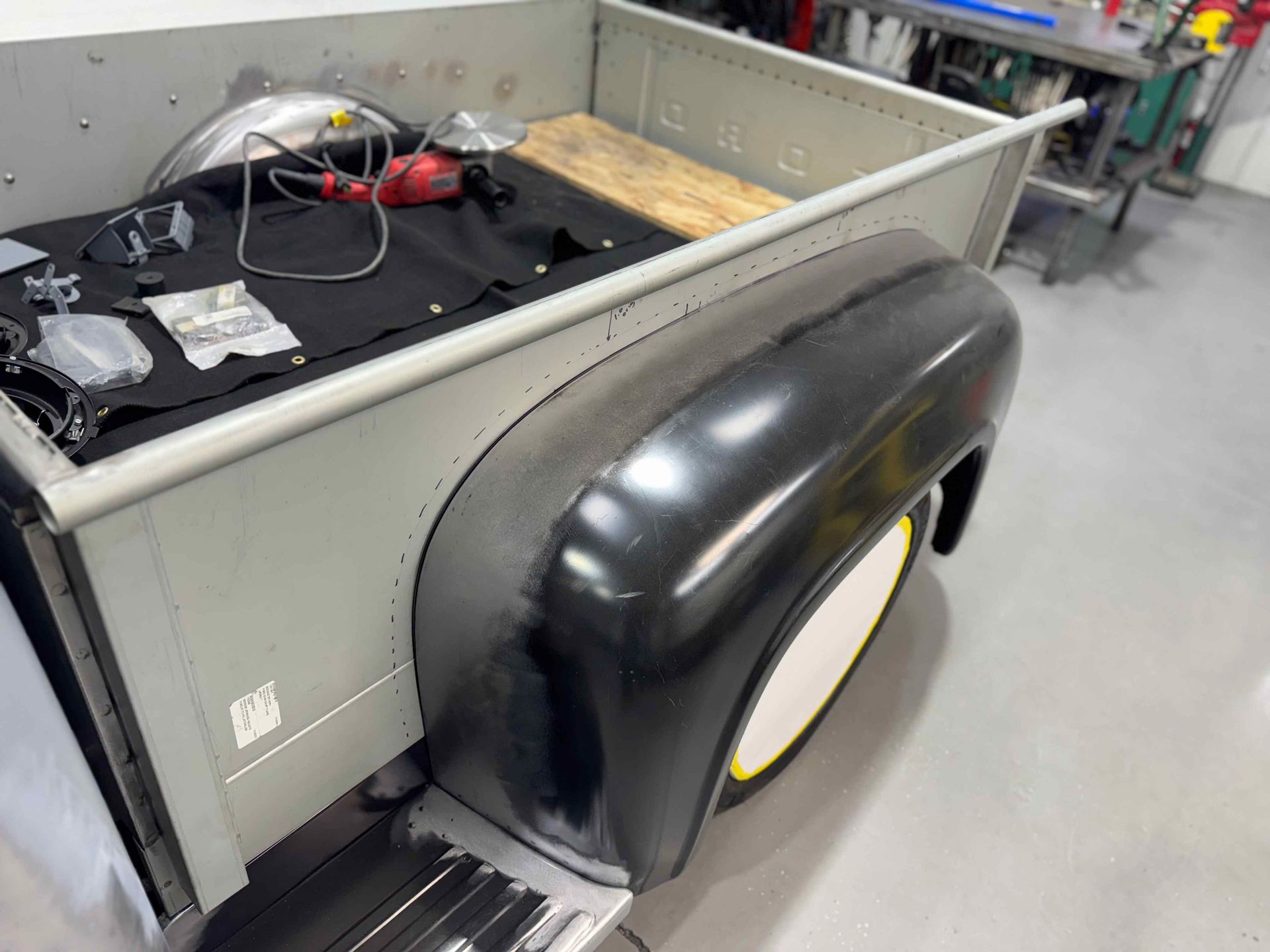 Small utility trailer with a black wheel cover in a workshop garage