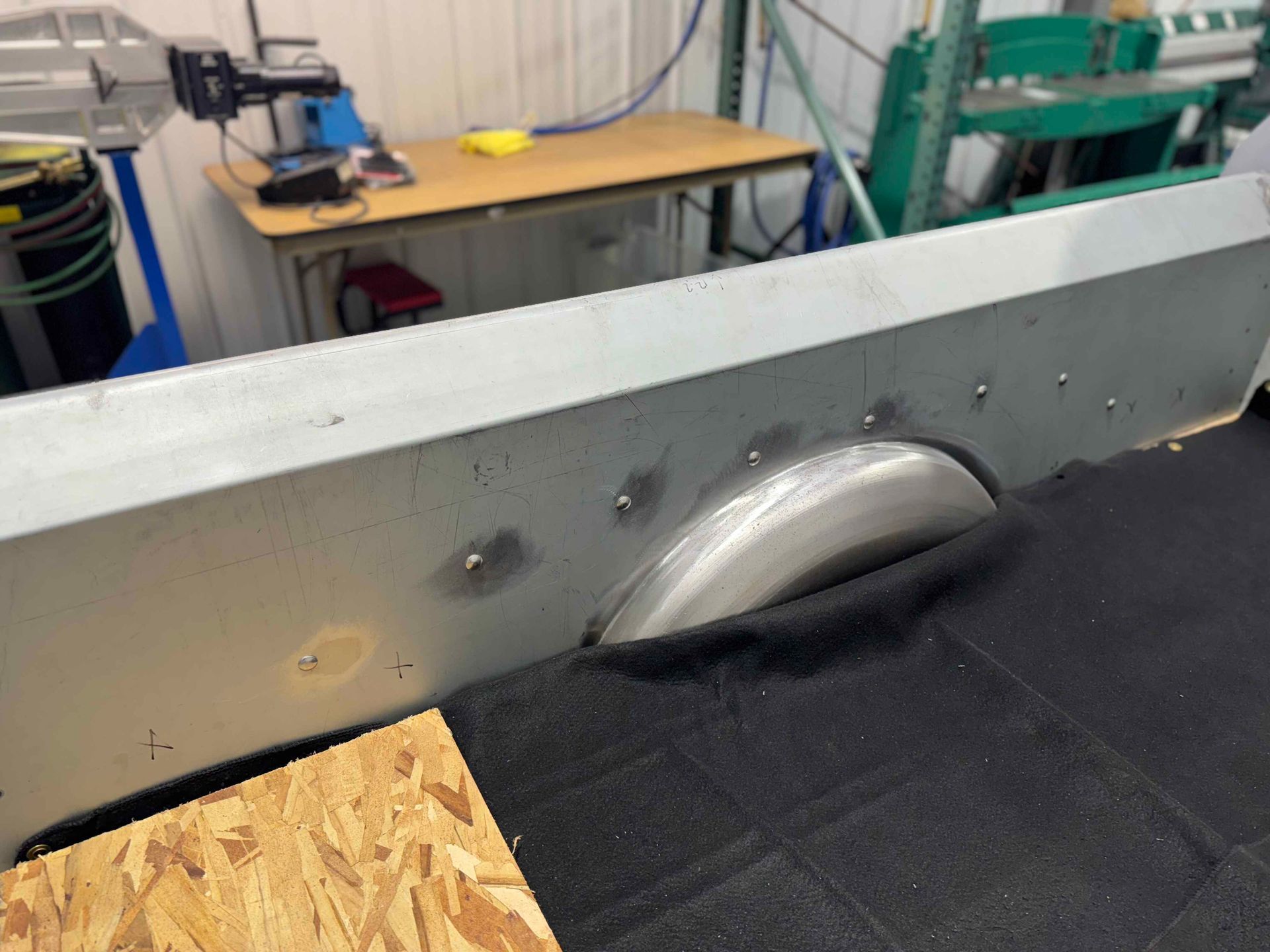 Workshop table saw with circular blade and black dust cover in a workshop.