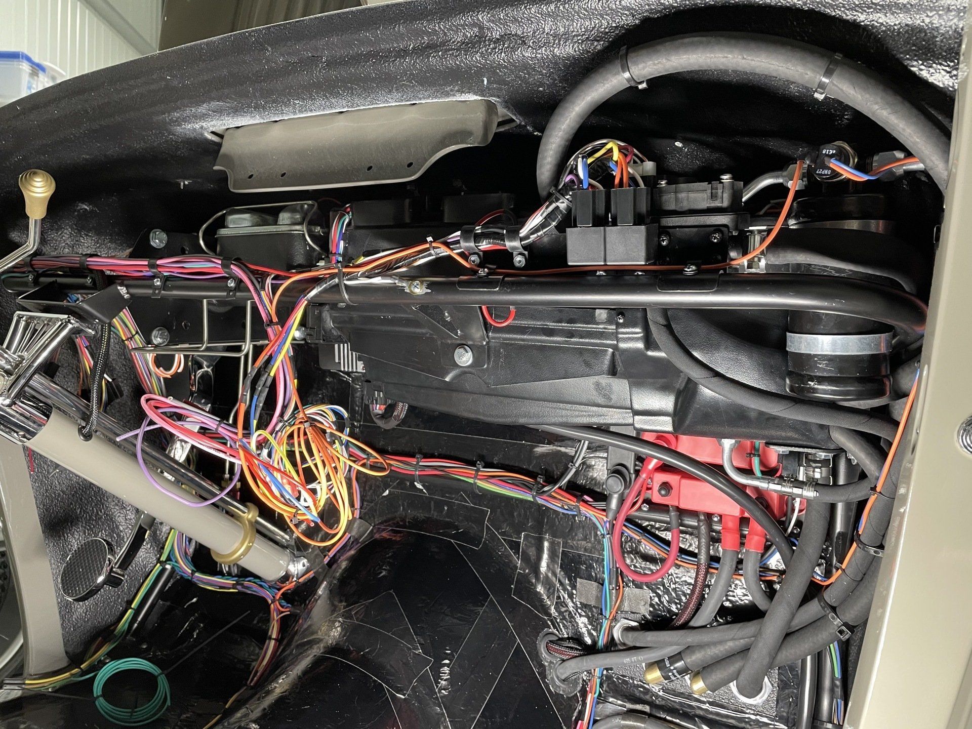 Close-up of a car’s exposed dashboard wiring and components behind the glovebox