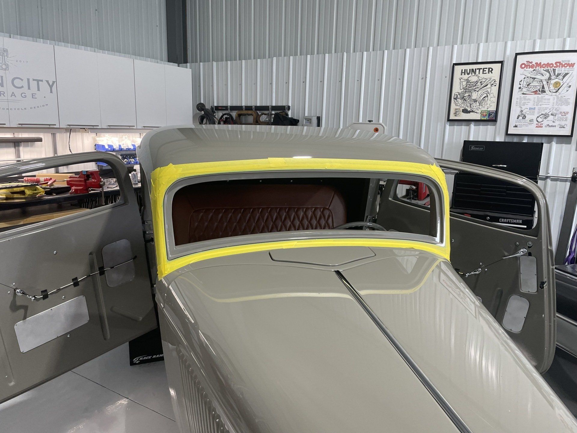Vintage car with yellow roof and gray body displayed indoors in a showroom