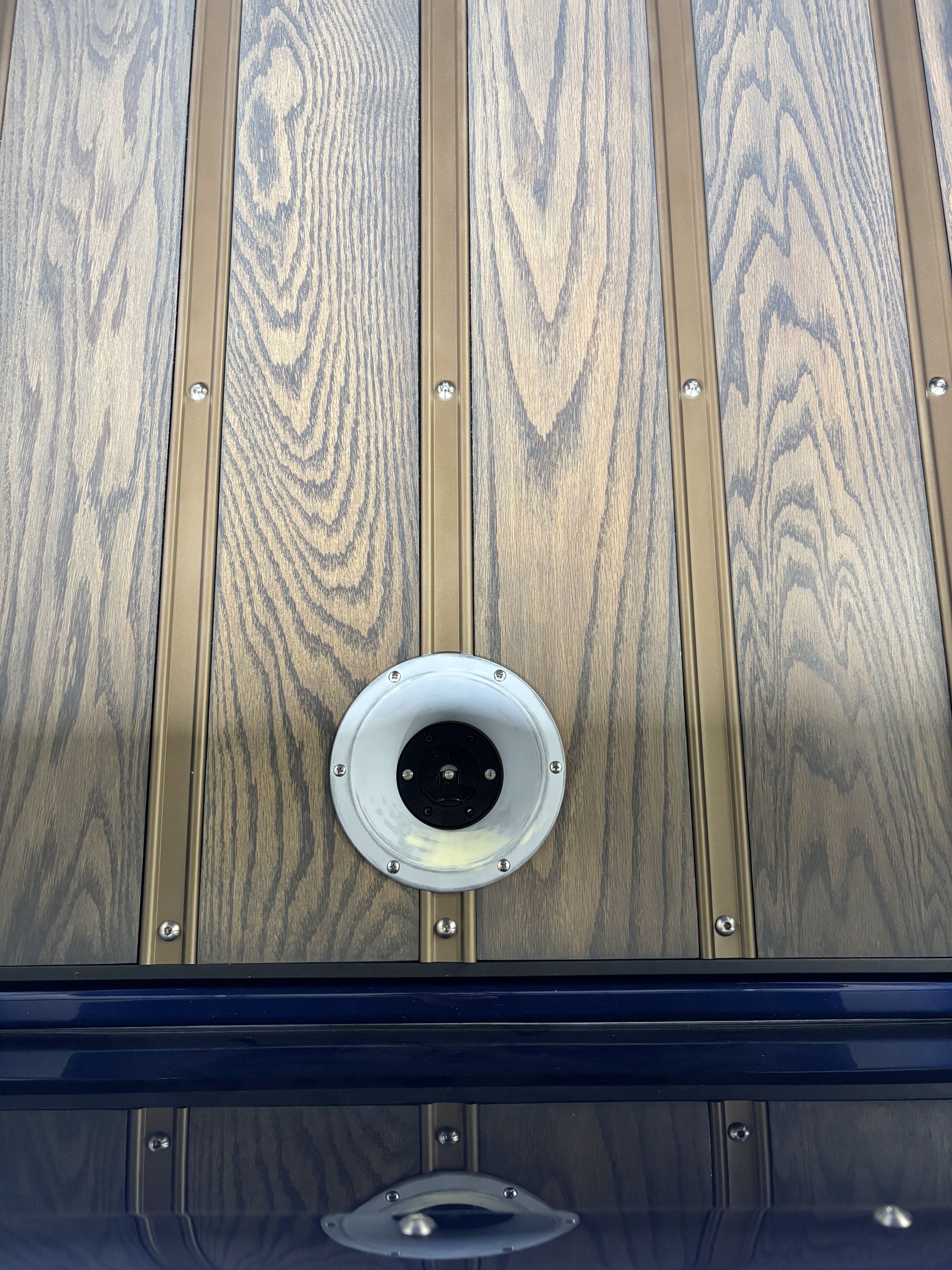 Wood-paneled wall with a round white-and-black fixture centered above a glossy dark surface.