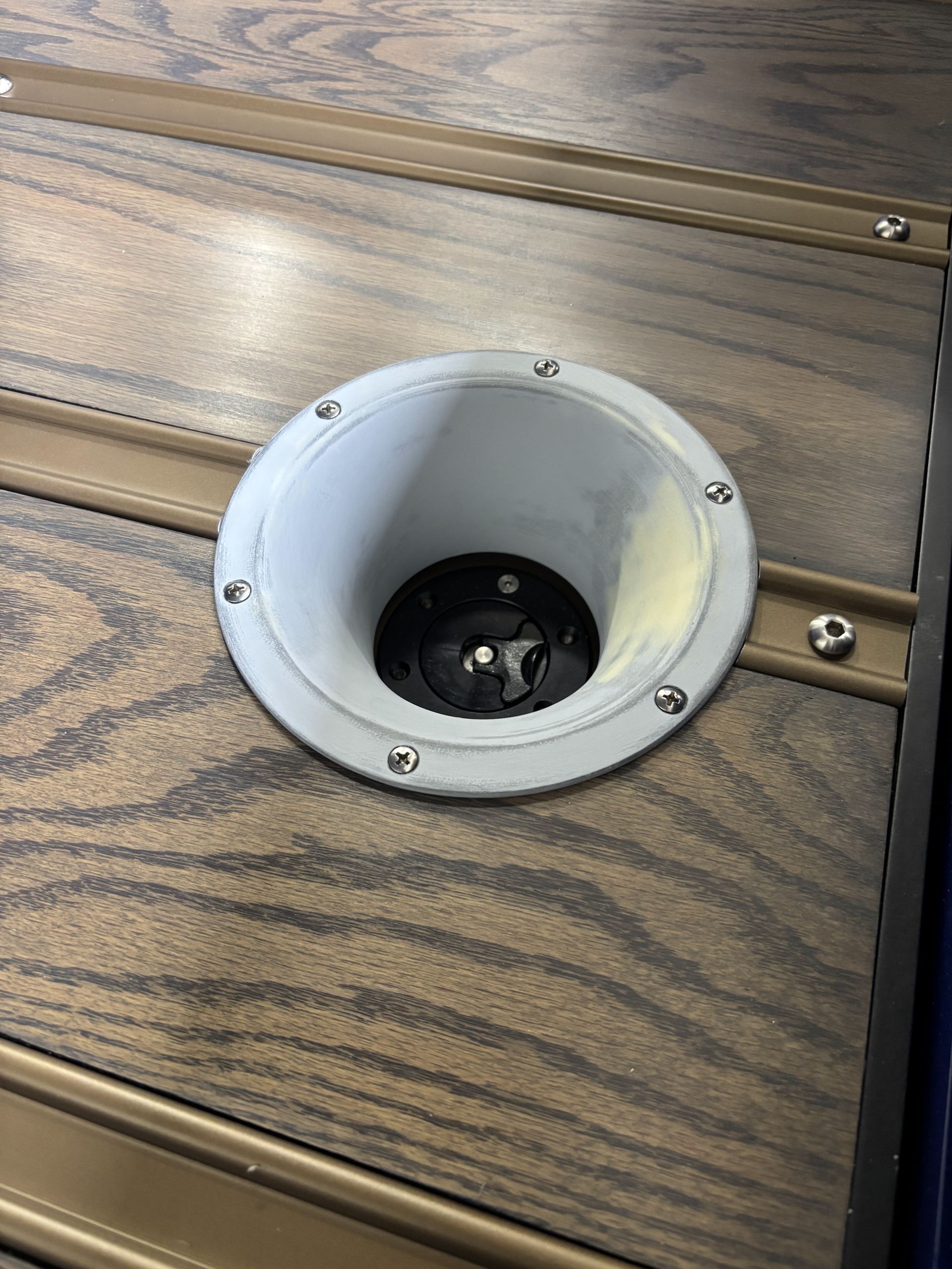 White recessed cup holder set into wood-grain deck panel.