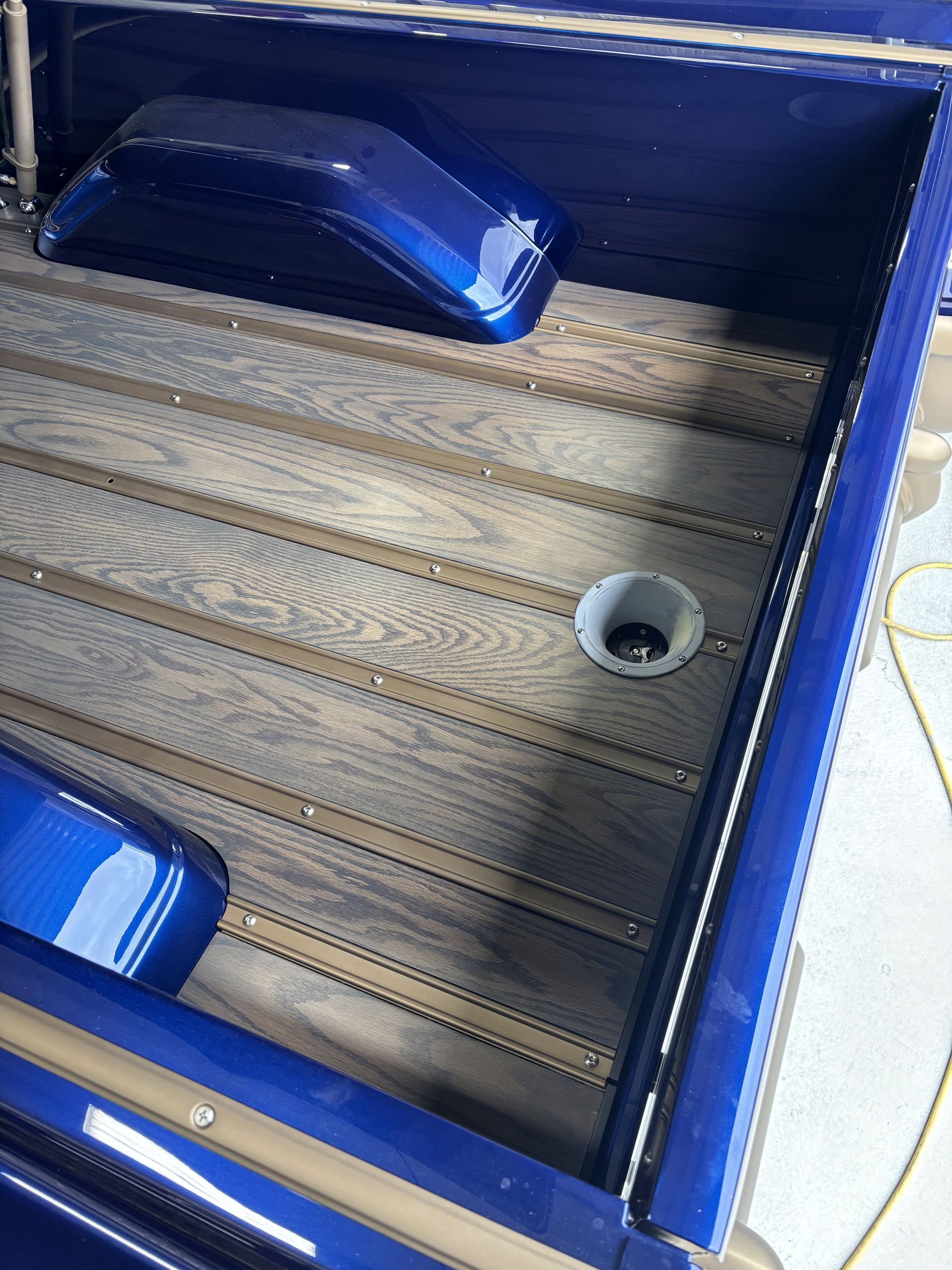 Blue-framed boat deck with wooden flooring, built-in seating, and a cup holder.