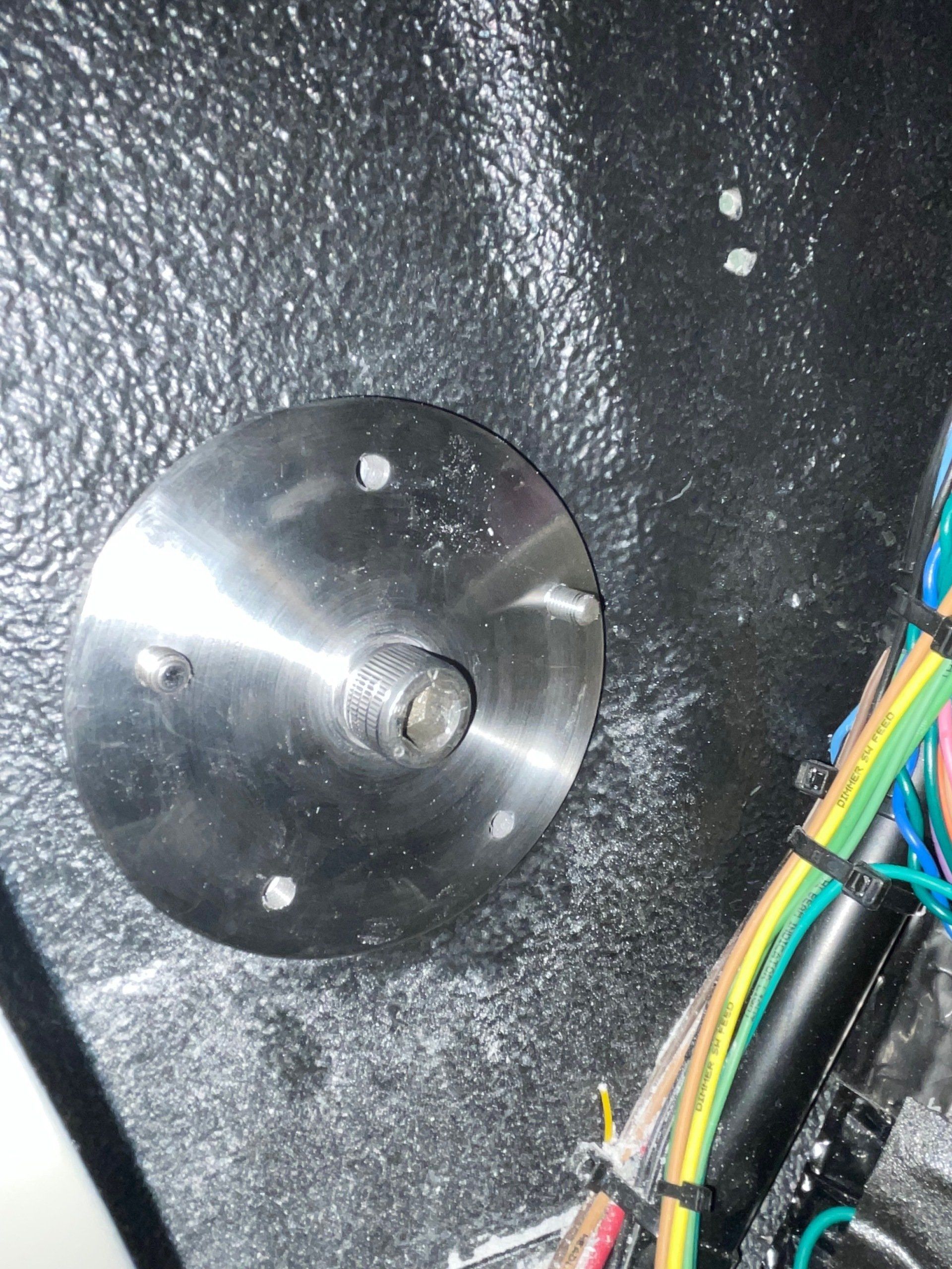 Close-up of a metal disk and multicolored wires on a dark textured surface.