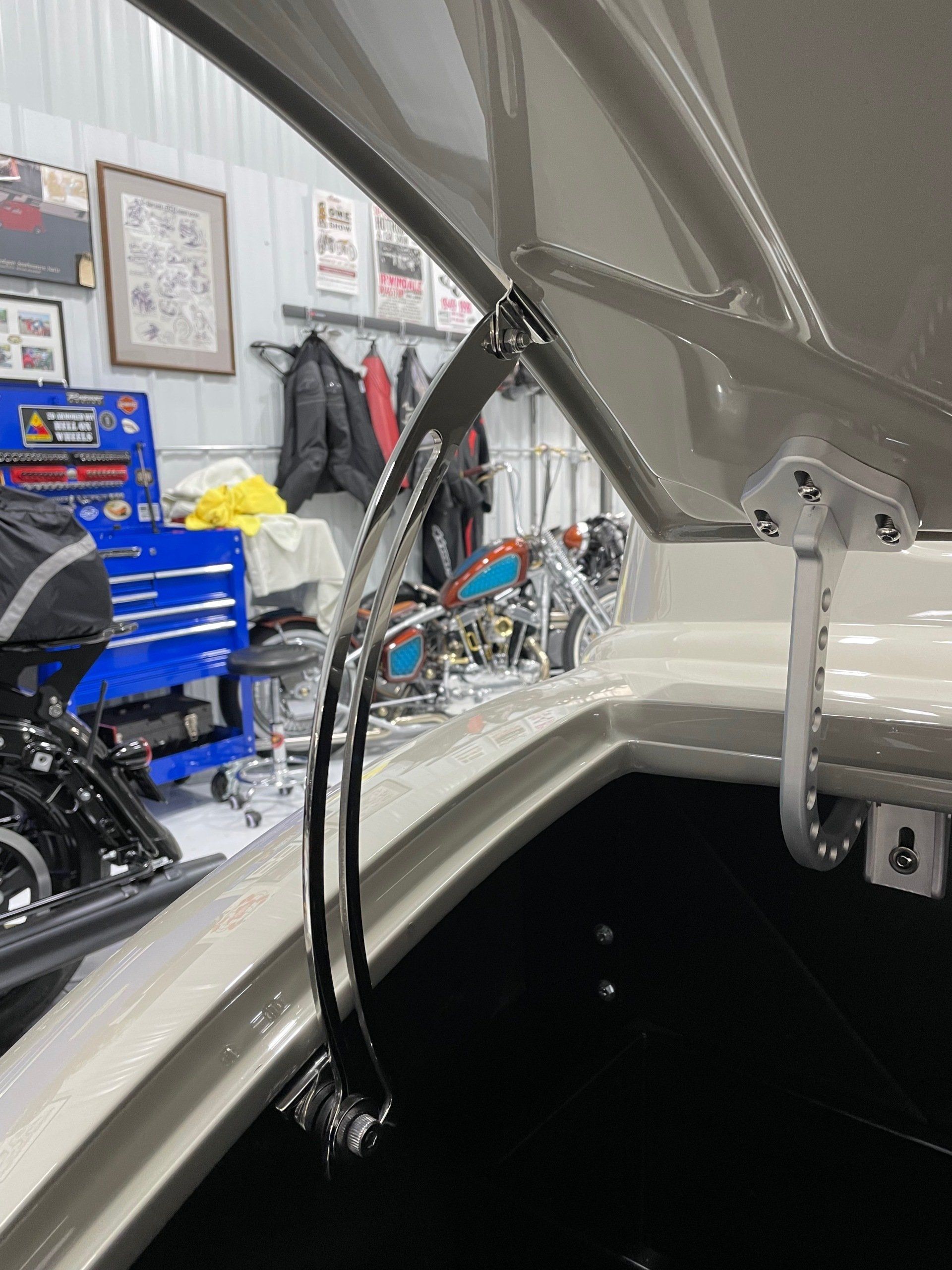 Boat hatch with black cables and chain inside a garage, with blue tool cabinets in the background