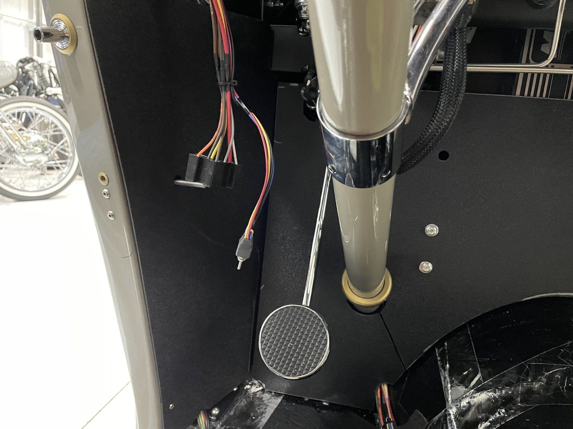 Black panel with hanging wires and a metal tube inside a machine or cabinet