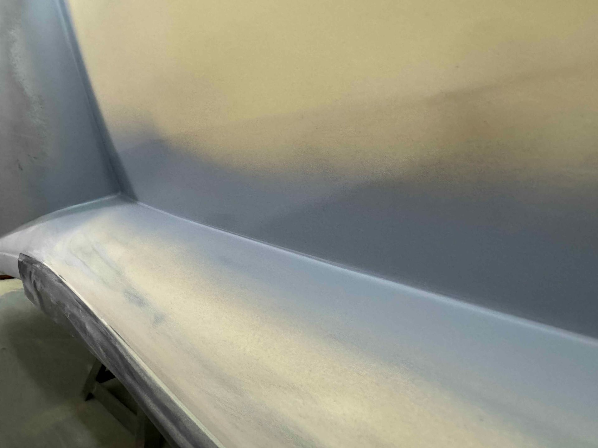 Curved gray bench or seat in a softly lit room, seen from close up.