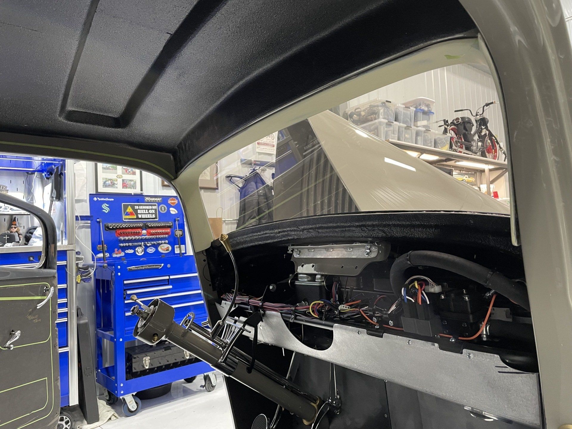 Inside a car workshop, a partly disassembled vehicle interior is shown beside blue tool cabinets.