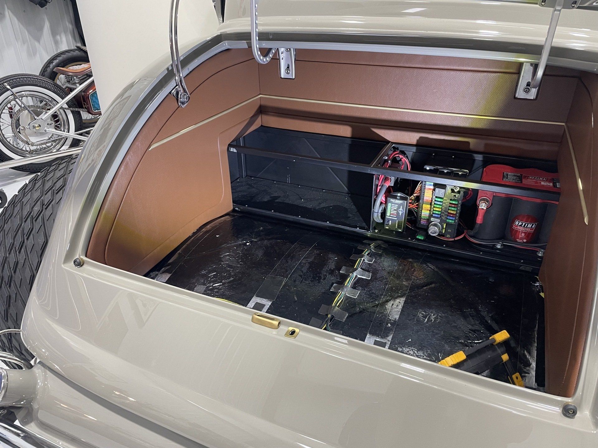 Car trunk with custom black cargo platform and storage compartments open inside a beige SUV