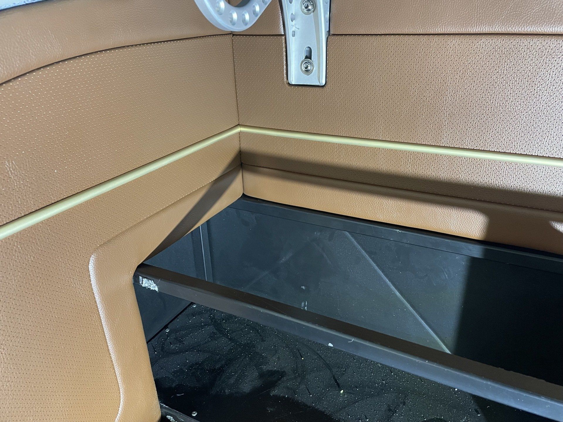 Corner of a tan room with a black shelf or cabinet and a metal bracket mounted above it.