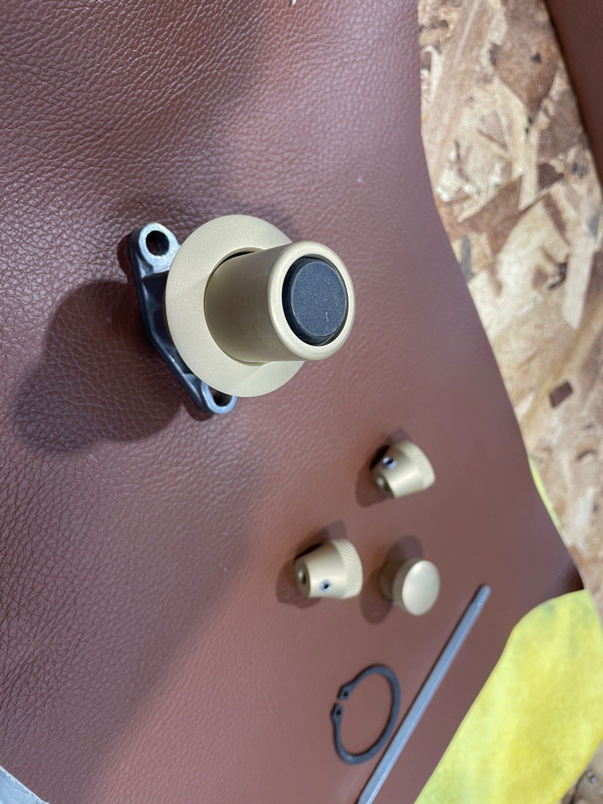 Disassembled beige and black mechanical knob parts on a brown surface, with a washer and small ring nearby