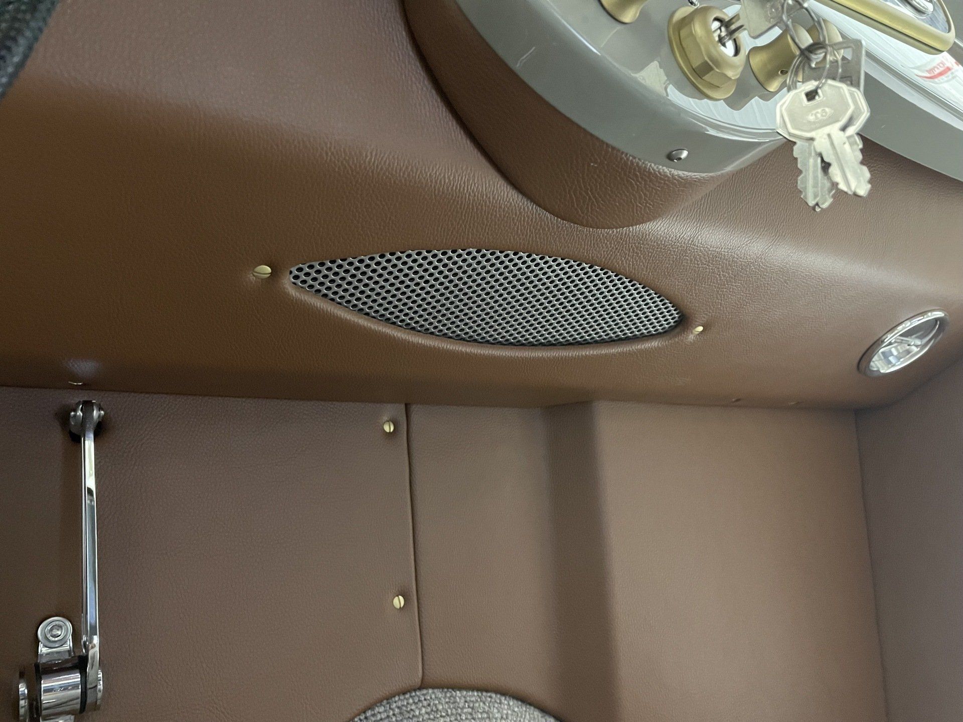 Brown car interior with keys in the ignition and a small mesh vent on the dashboard