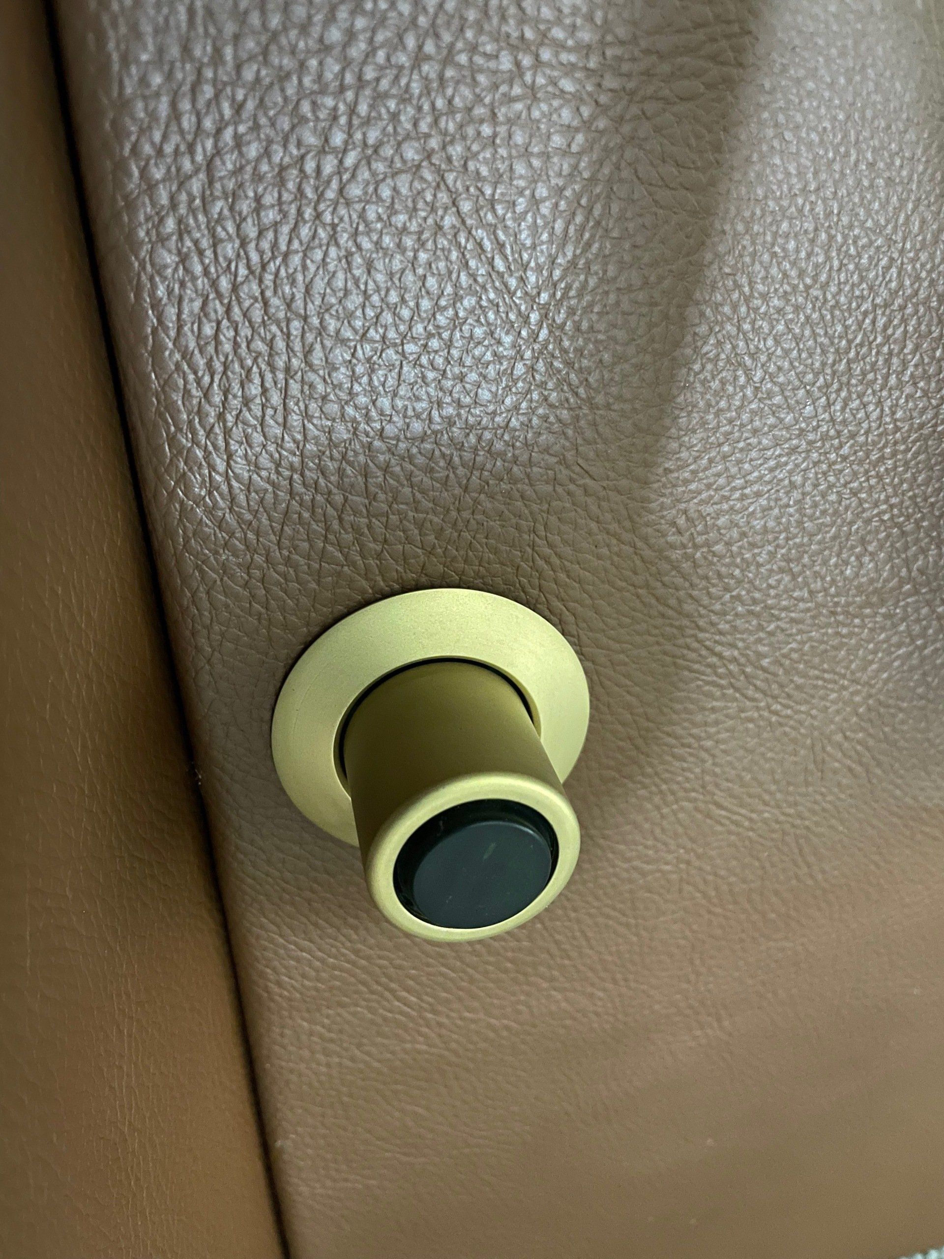 Close-up of a brass and black door knob on a textured brown leather surface
