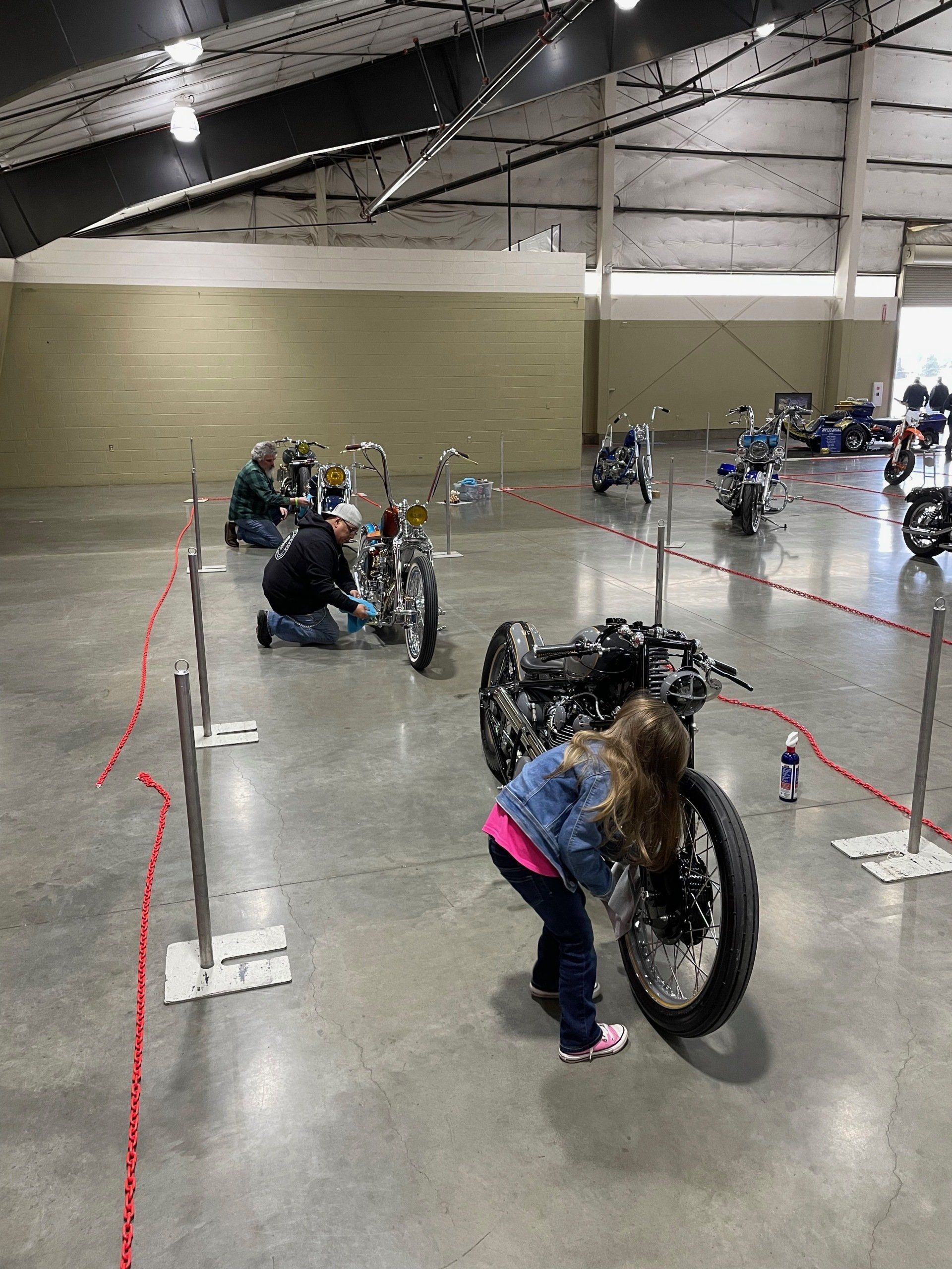 People in a large hall working on bicycles, with one person bending over a bike wheel in the foreground.