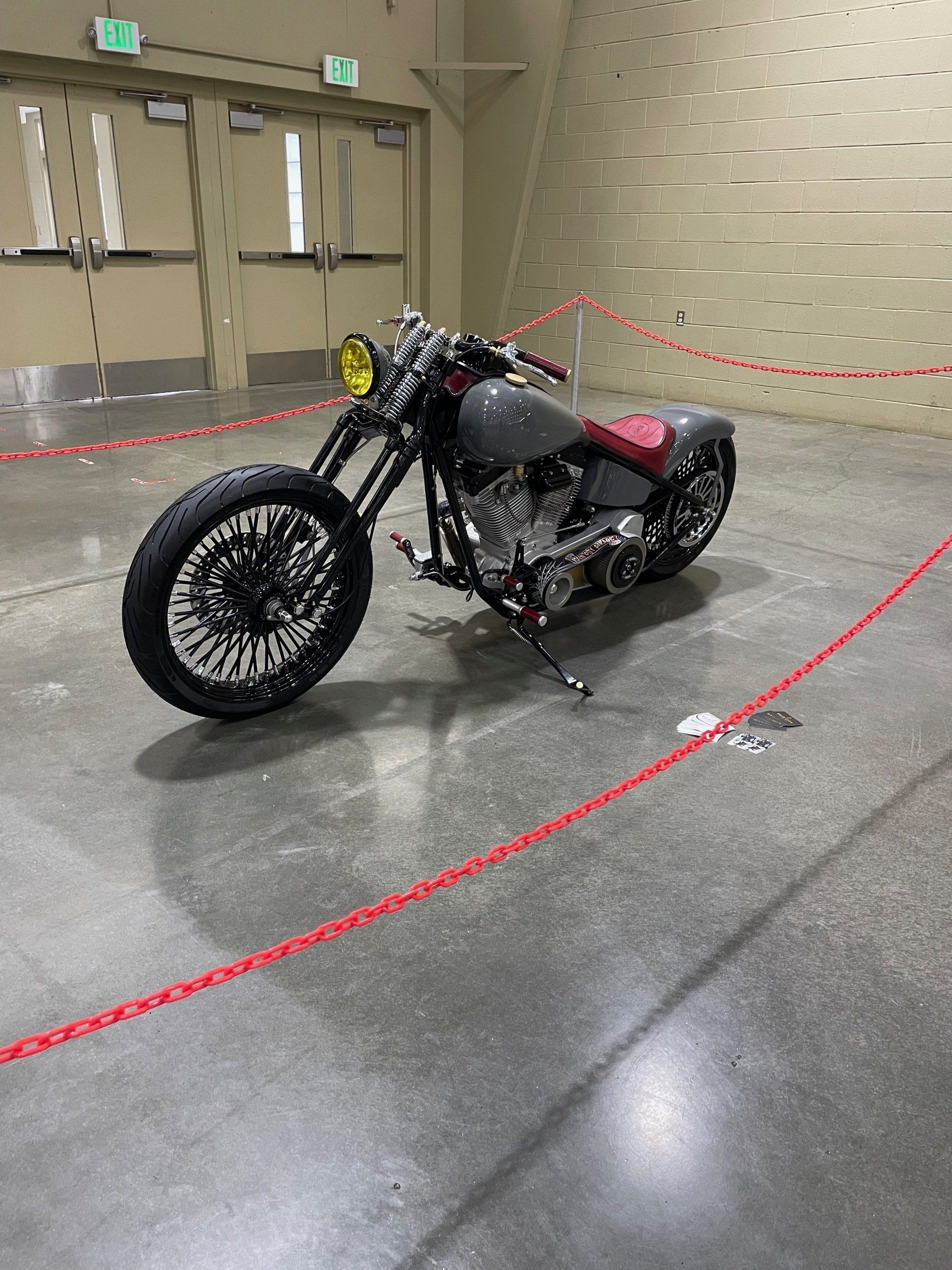 Custom black motorcycle on display indoors, roped off in a convention hall.