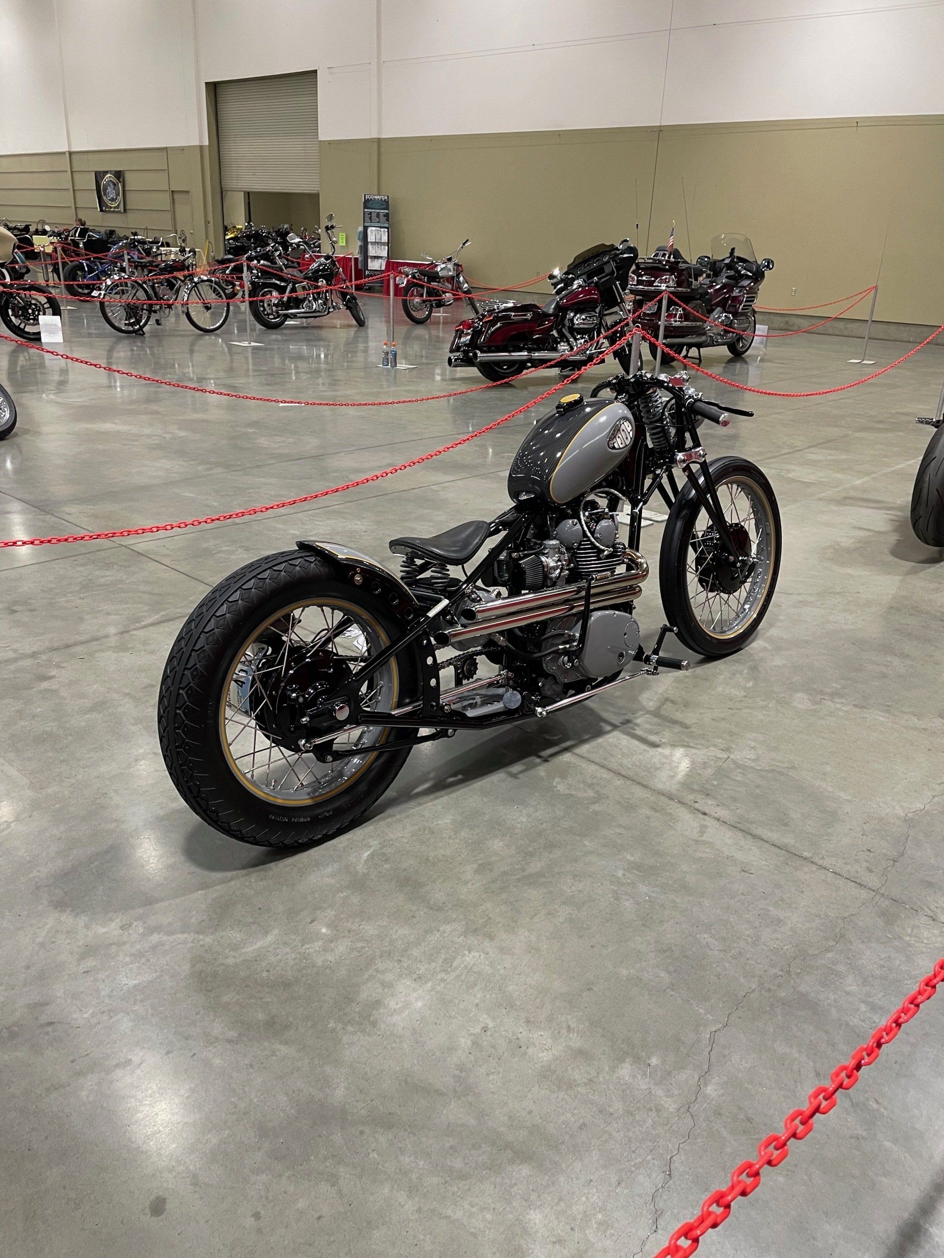 Custom black motorcycle on display in an indoor showroom, surrounded by other bikes.