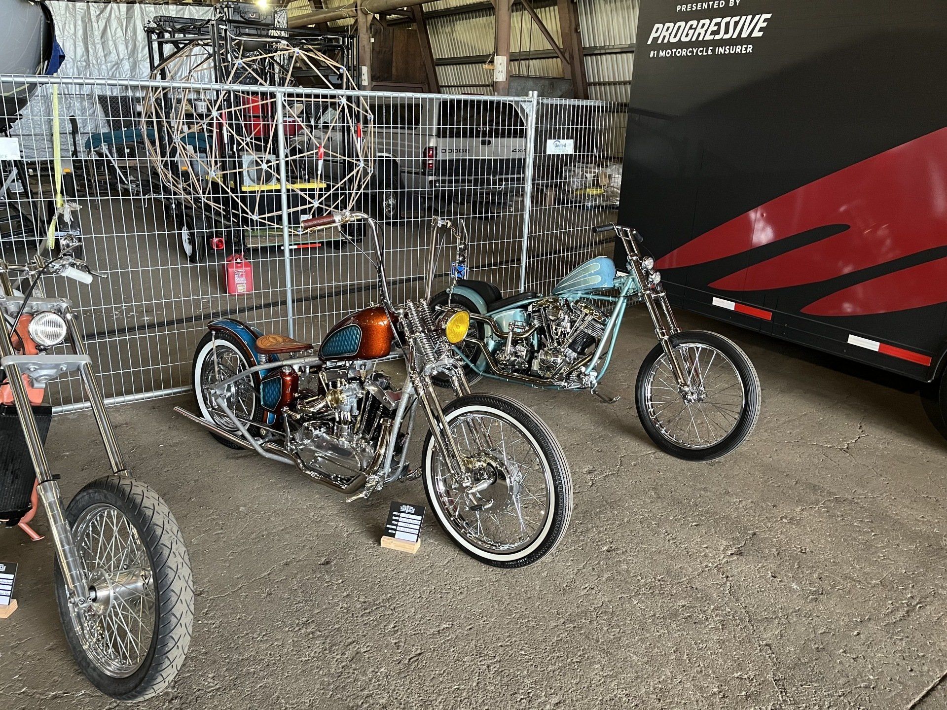 Several recumbent trikes displayed at a bike show beside a black-and-red van