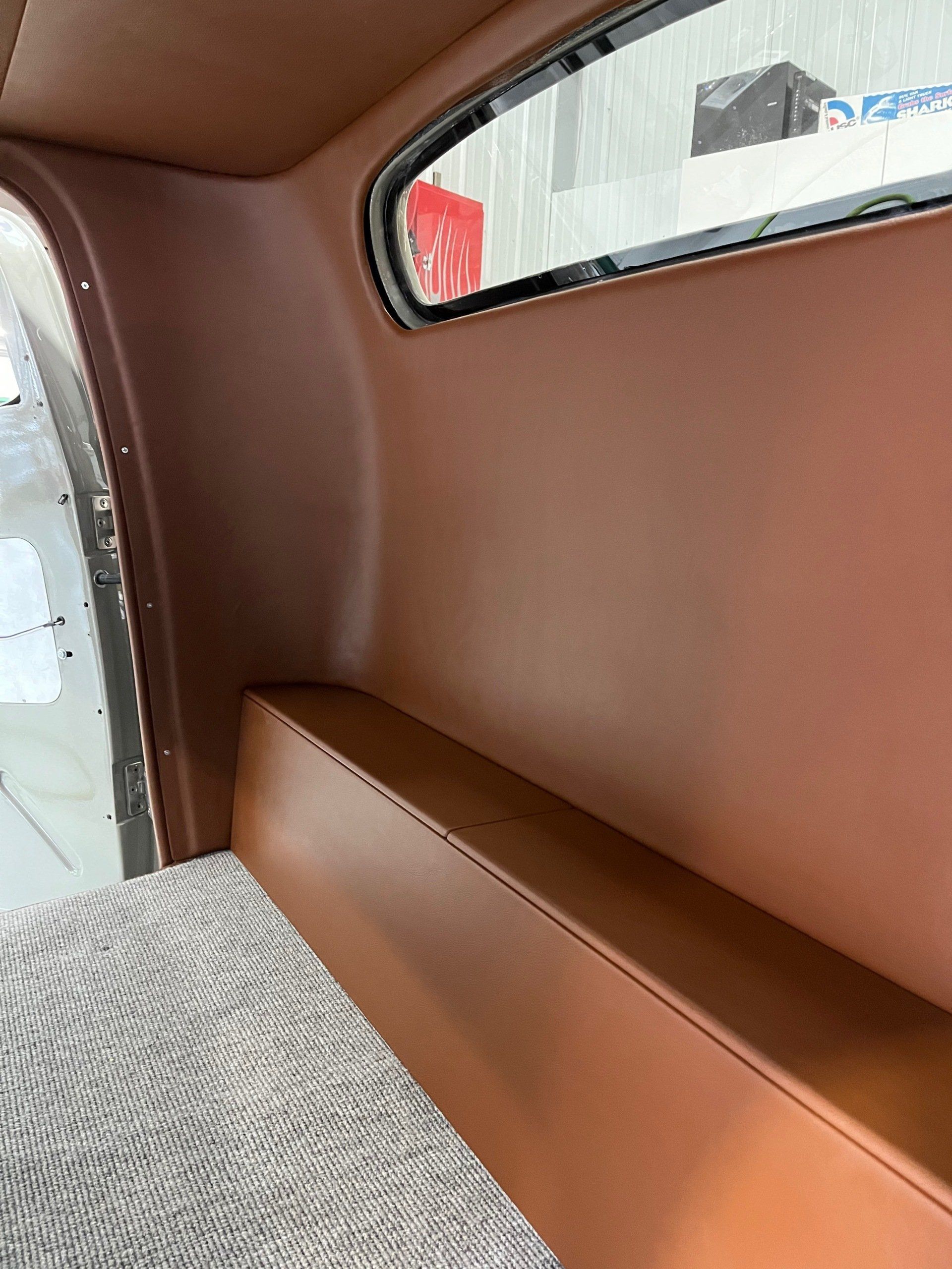 Brown car interior with a gray seat and a small rear window view