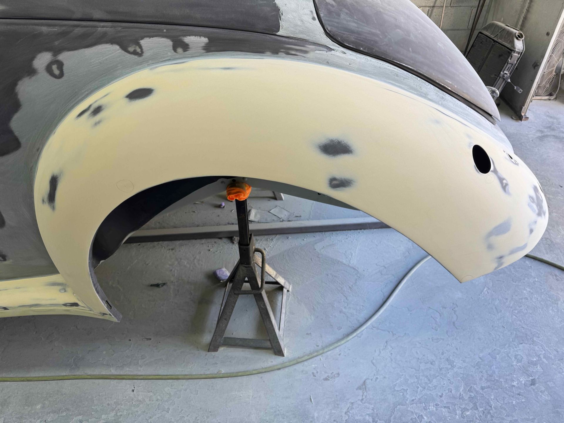 Car body panel under repair, propped on a jack stand in a workshop.