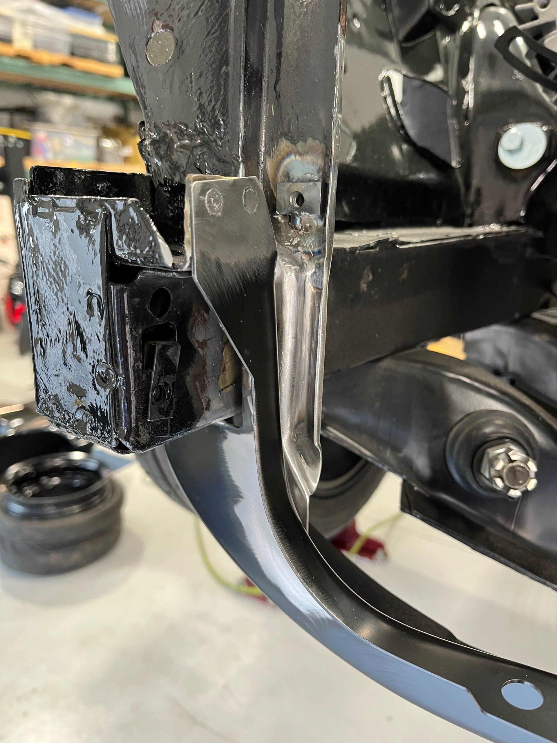 Close-up of a greasy black metal bike or machine joint with bolts and a curved bracket